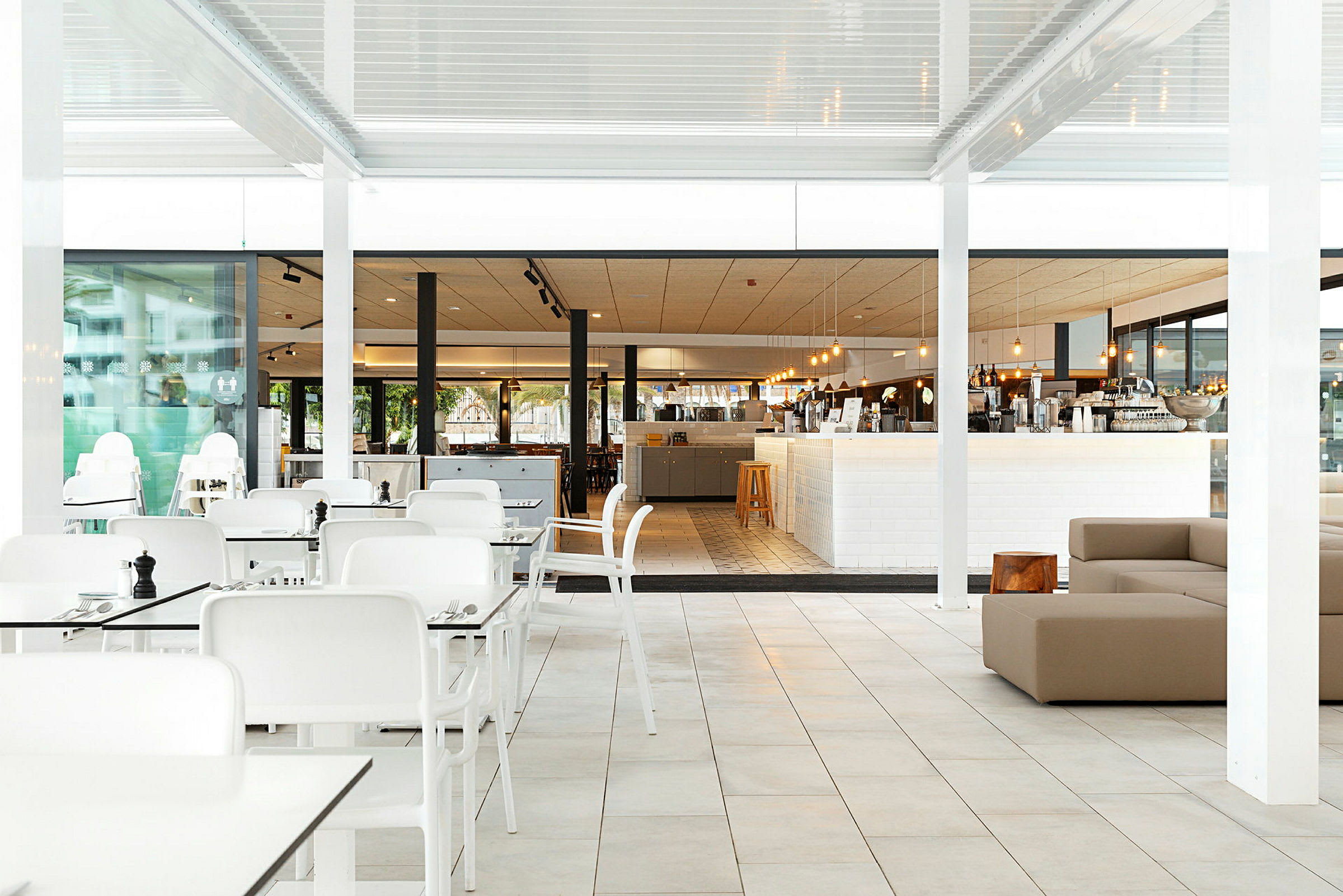 Billedet viser en restaurant med hvide borde og stole samt en lys spisesal. (AI-genereret tekst)