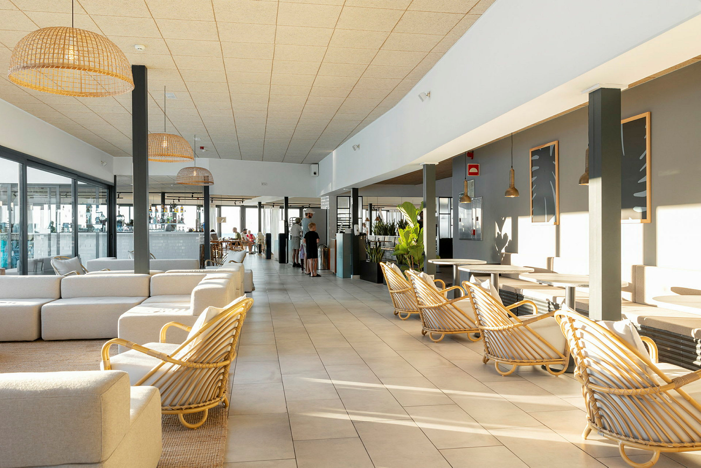 Et solrigt hotelværelse med lyse møbler og store vinduer. (AI-genereret tekst)