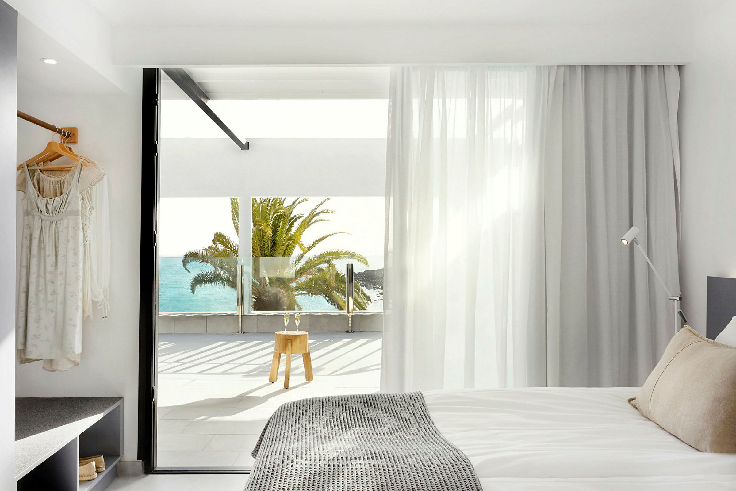 Moderne hotelværelse med udsigt til havet og en palme uden for vinduet. (AI-genereret tekst)