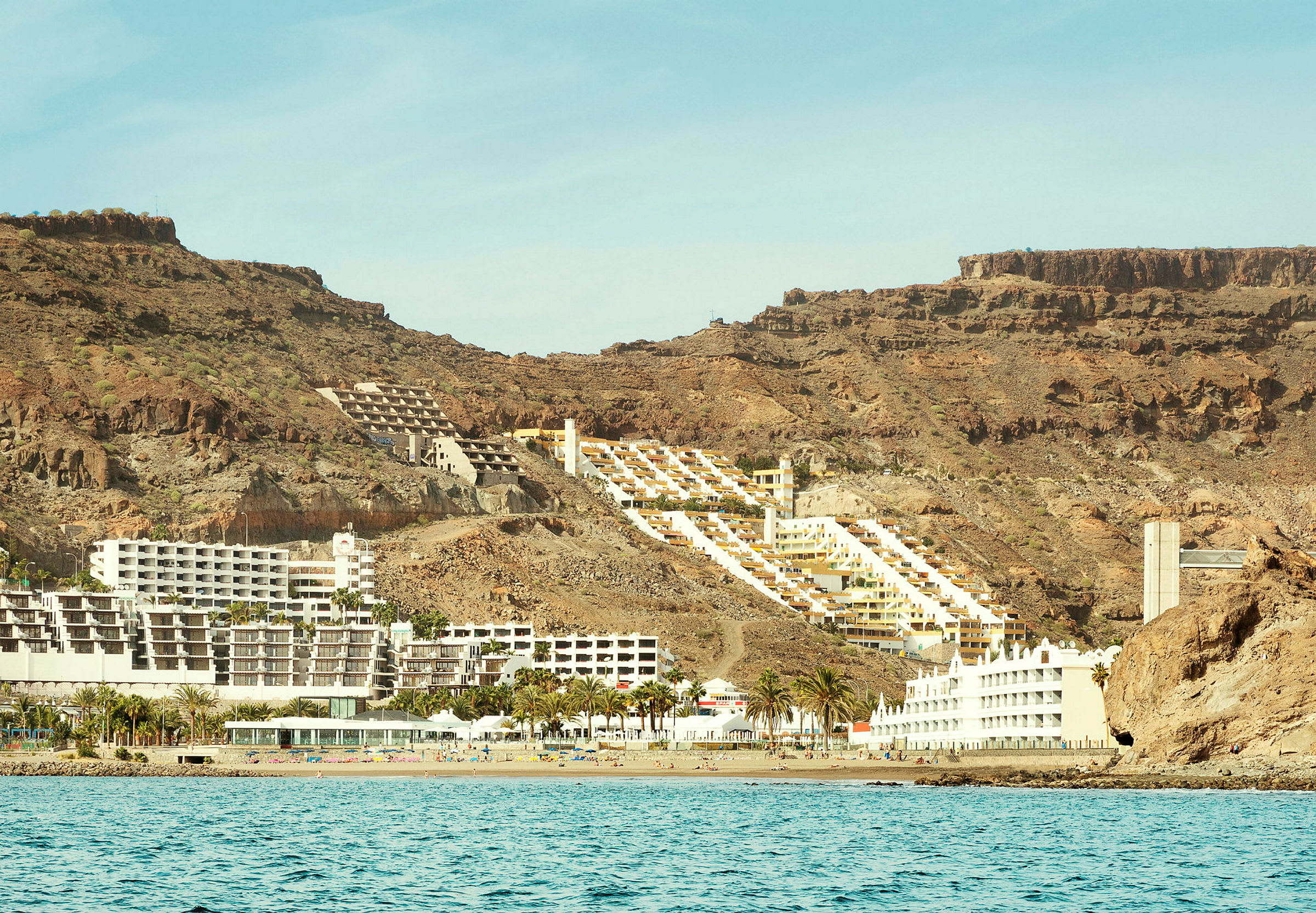 Hotelbygninger ved en klippekant tæt på havet. (AI-genereret tekst)