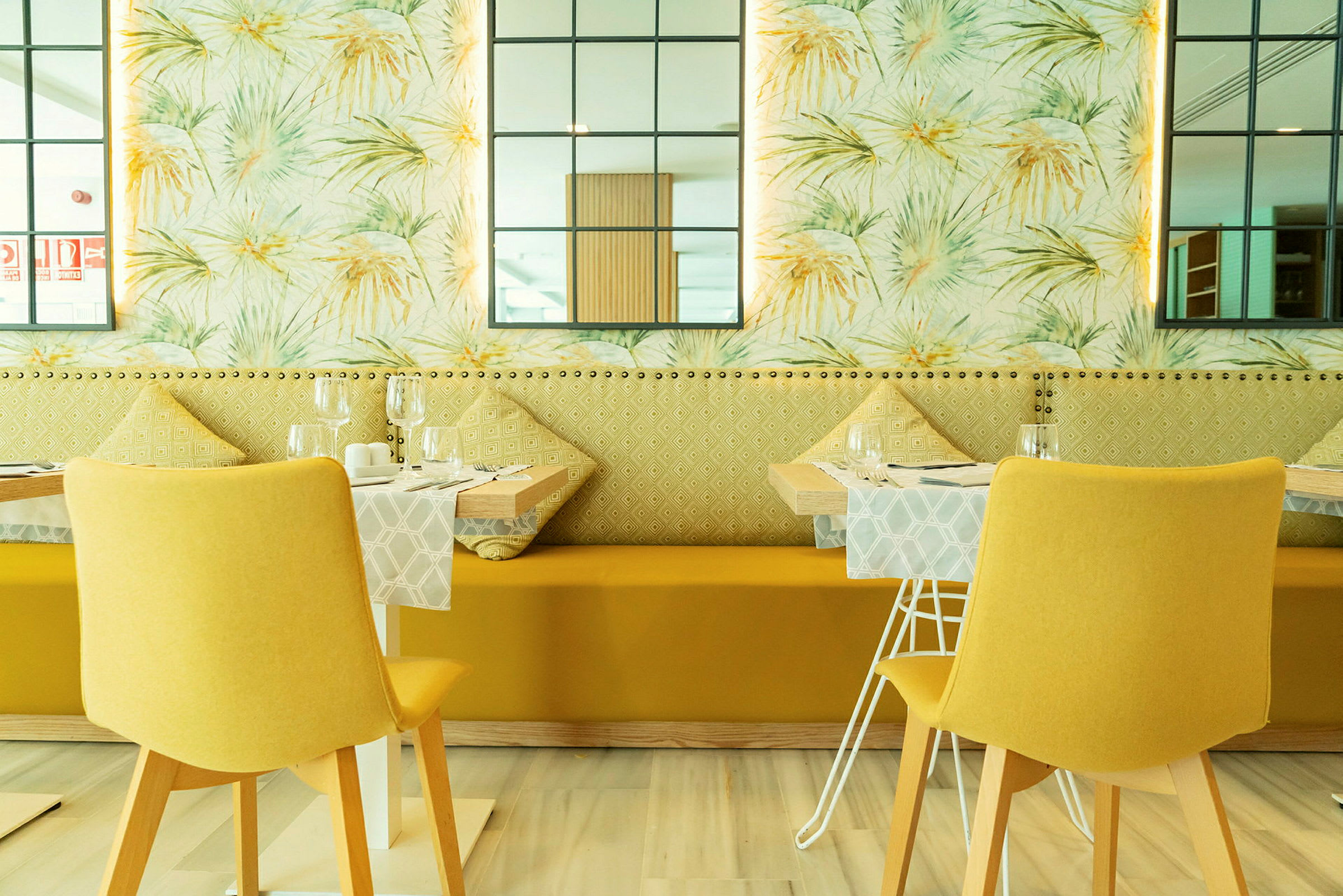 Restaurant med moderne indretning, gule stole og dekorative vægdetaljer. (AI-genereret tekst)