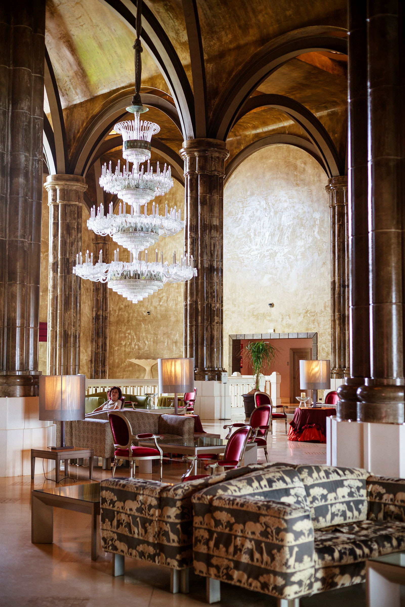 En hotellobby med luksuriøse dekorationer, herunder en stor krystallysekrone og møbler med dyremønster. (AI-genereret tekst)