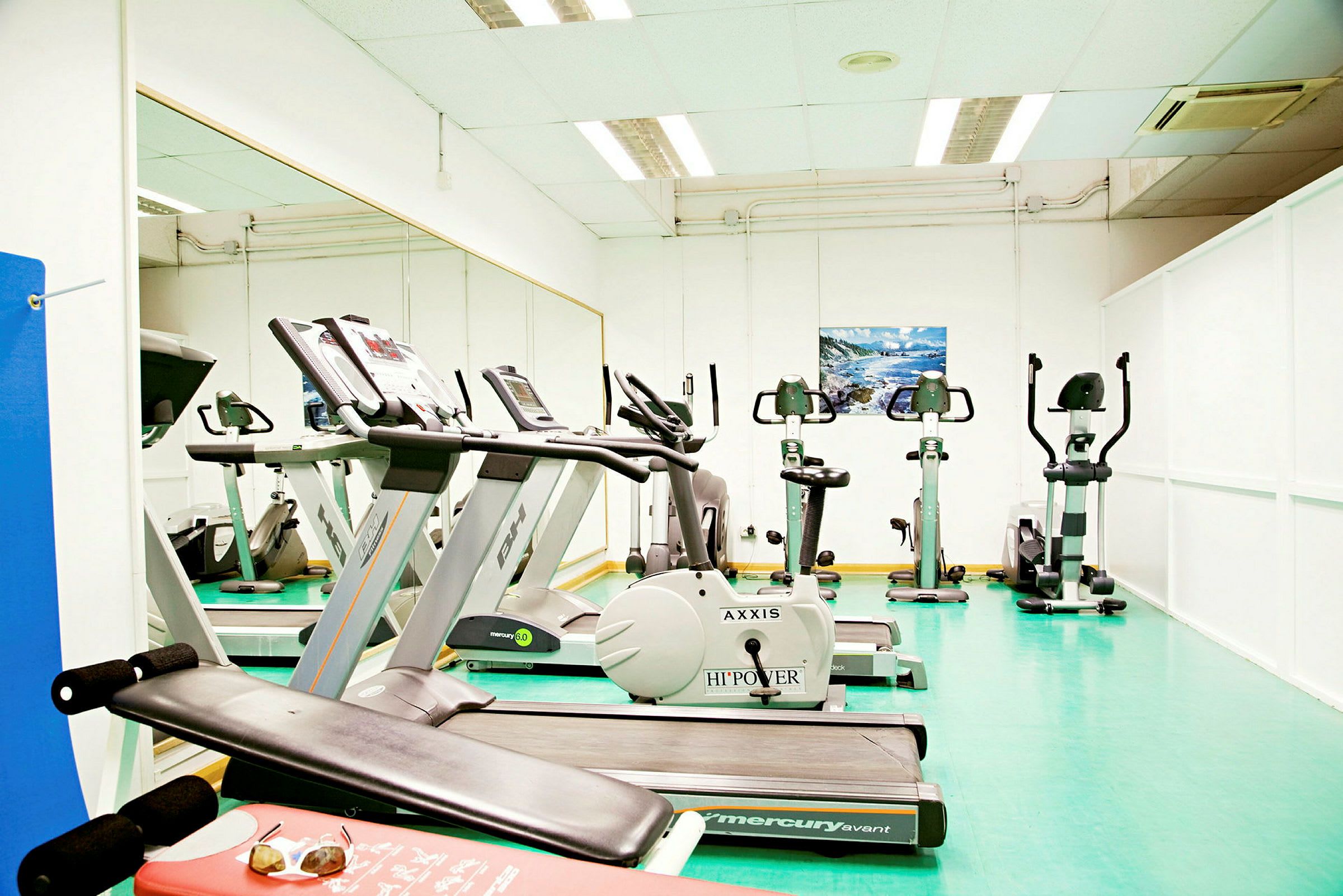 Et fitnesscenter med træningsmaskiner, herunder løbebånd og motionscykler. (AI-genereret tekst)