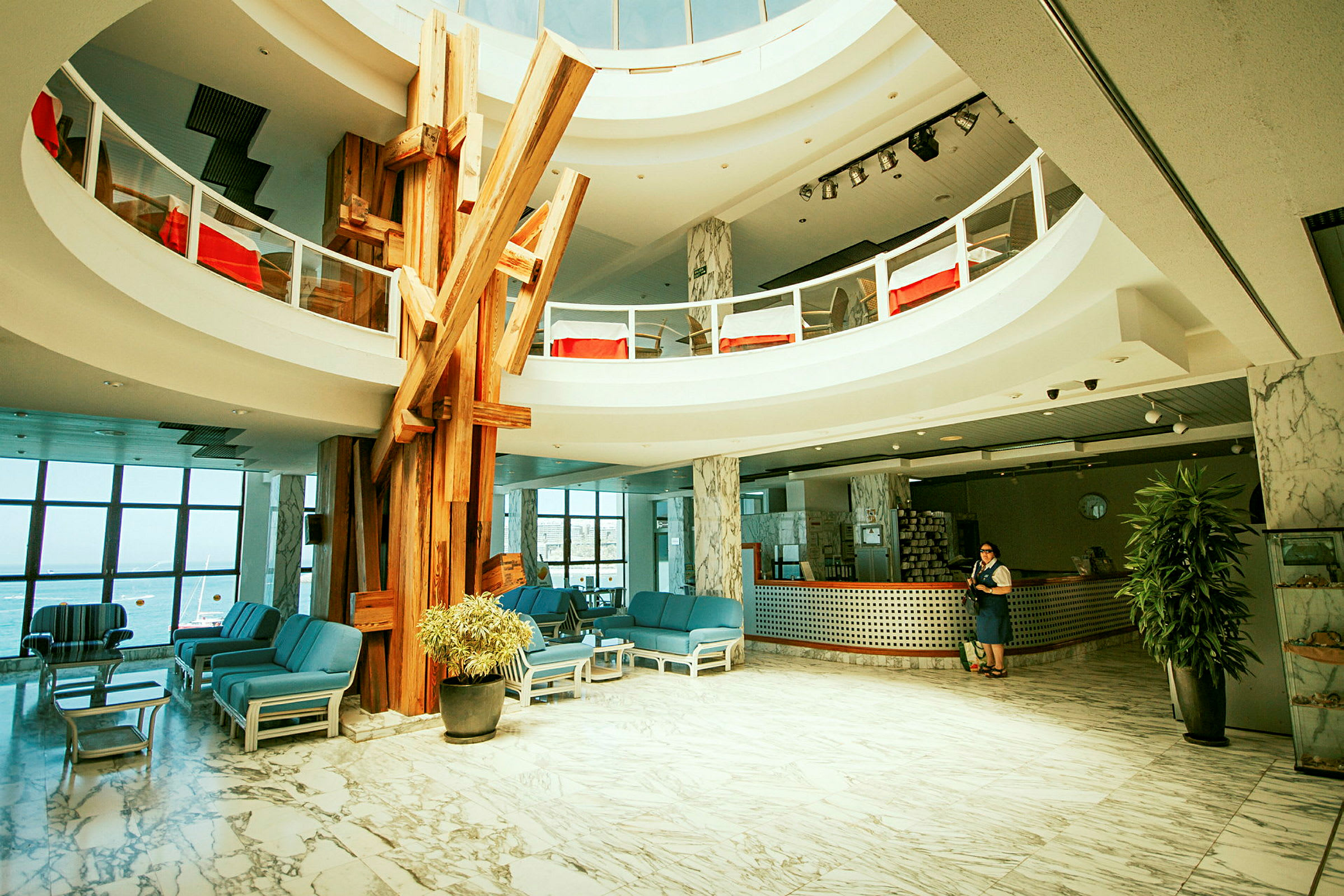 Hotellets lobby med siddegrupper, reception og dekorative træelementer. (AI-genereret tekst)