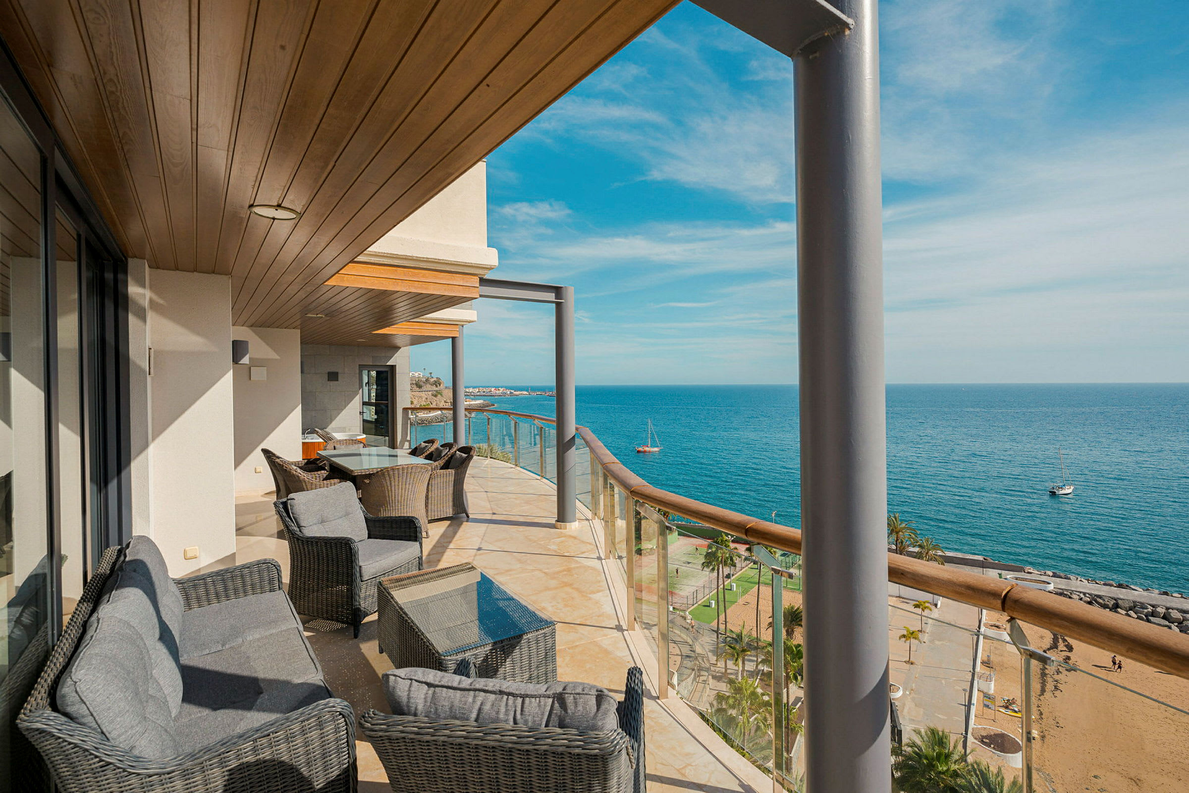 En balkon med siddepladser og udsigt over havet og stranden. (AI-genereret tekst)