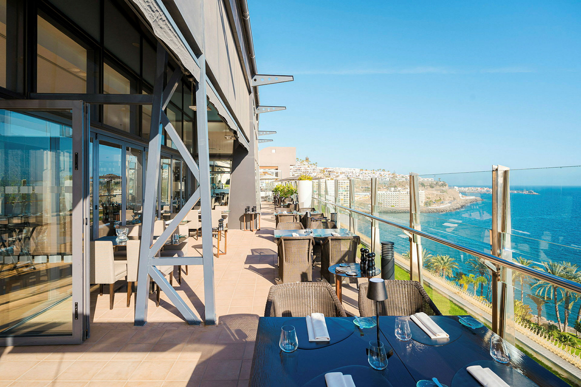 Restaurantterrasse med udsigt over havet og kystlandskabet. (AI-genereret tekst)