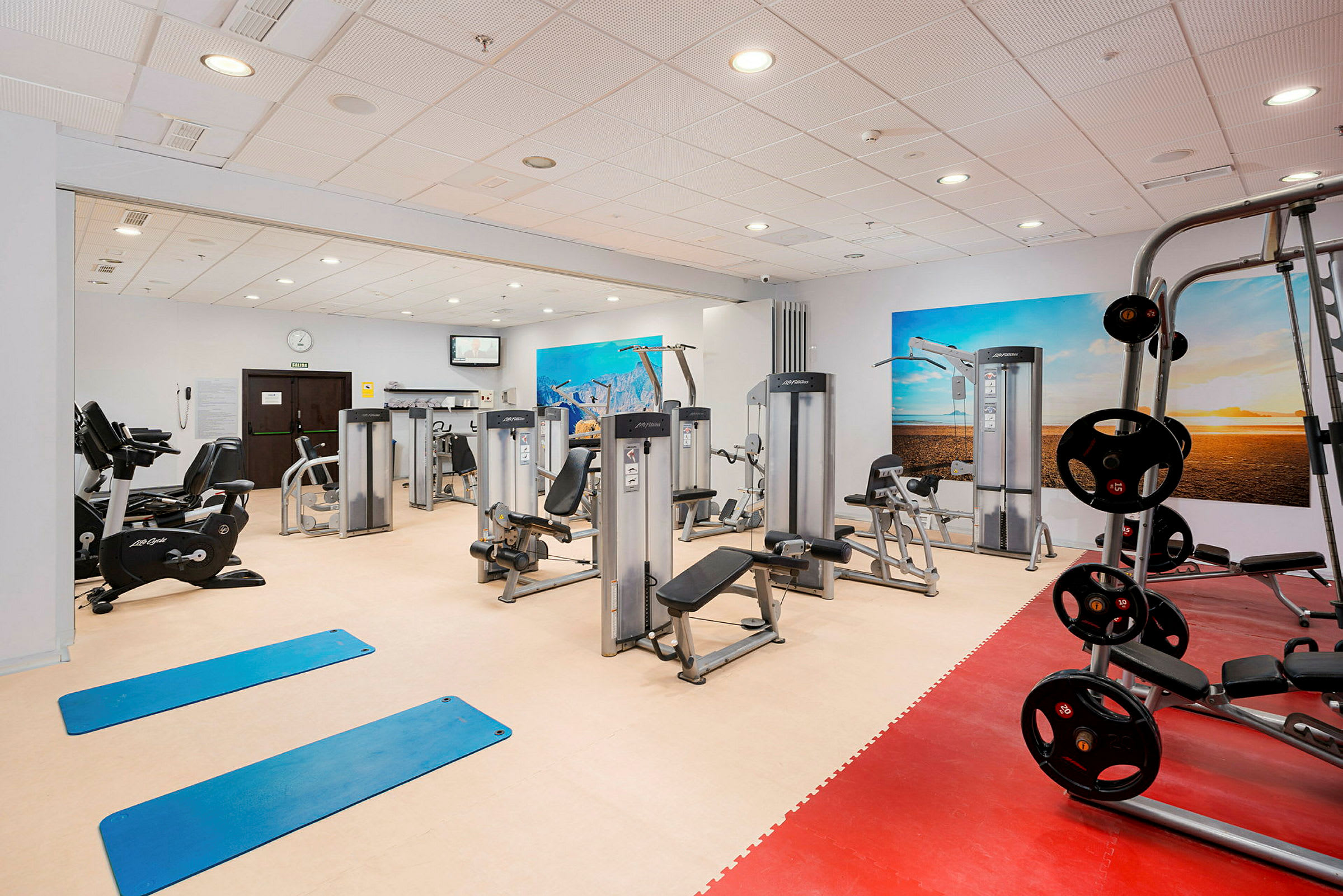 Fitnesscenter med forskellige træningsmaskiner og udstyr. (AI-genereret tekst)