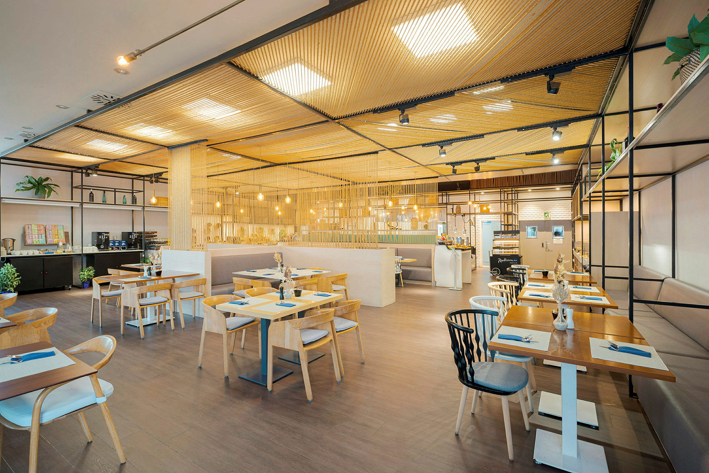 En moderne restaurant med træborde og stole, oplyst af hængende lamper. (AI-genereret tekst)
