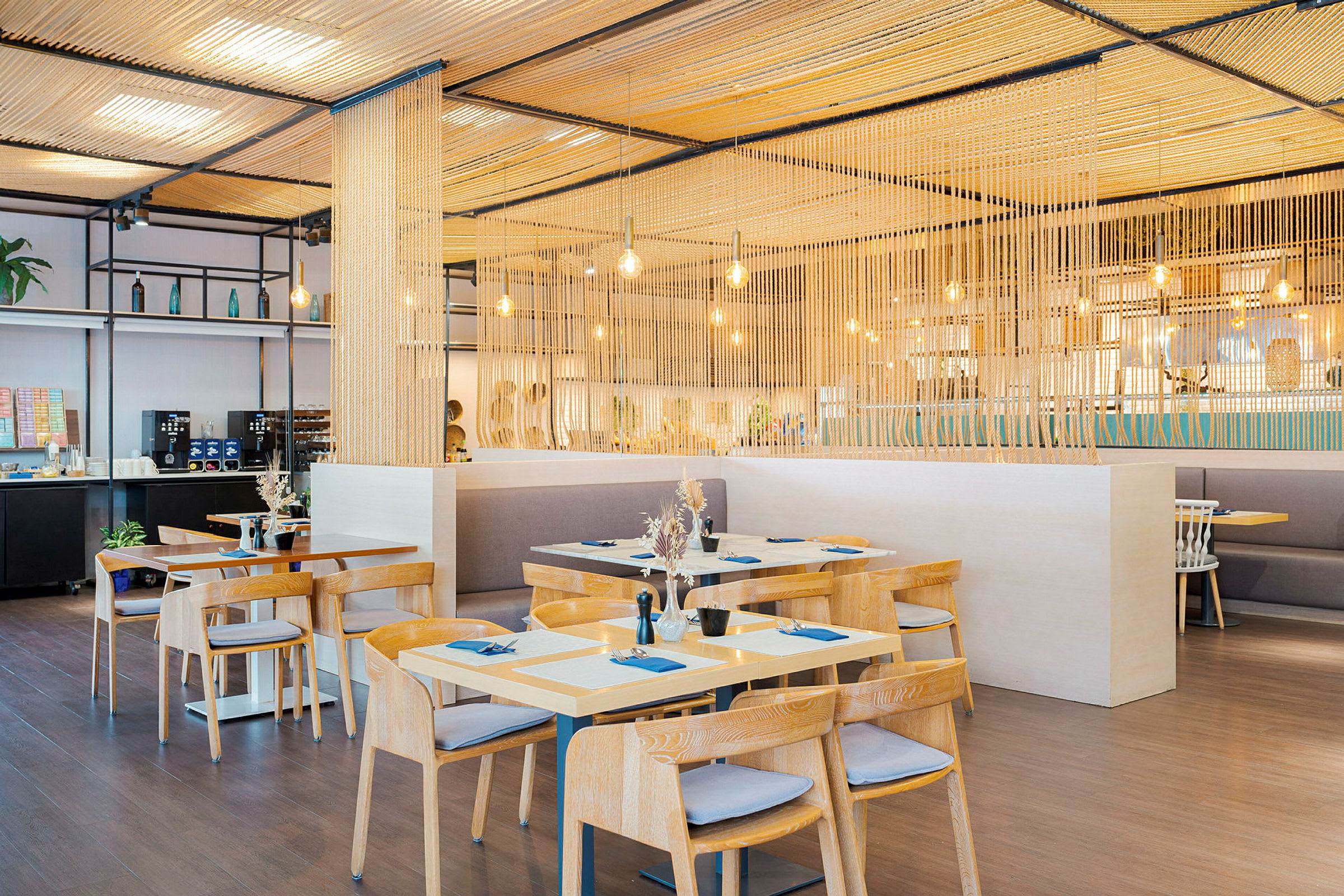 Moderne restaurant med træborde og stole, belyst med hængende lamper. (AI-genereret tekst)