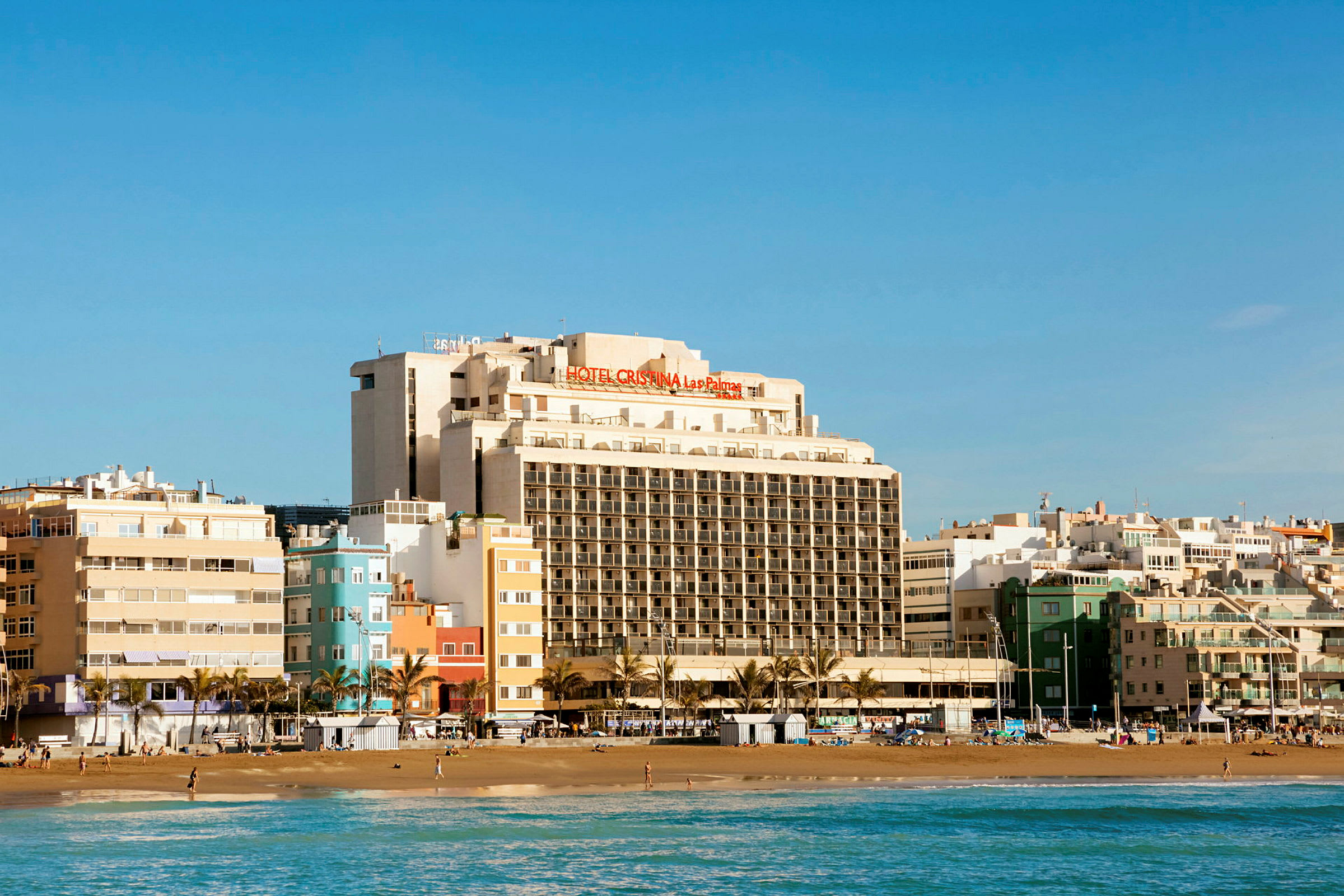 Udsigt over en strand med en stor hotelbygning i baggrunden. (AI-genereret tekst)
