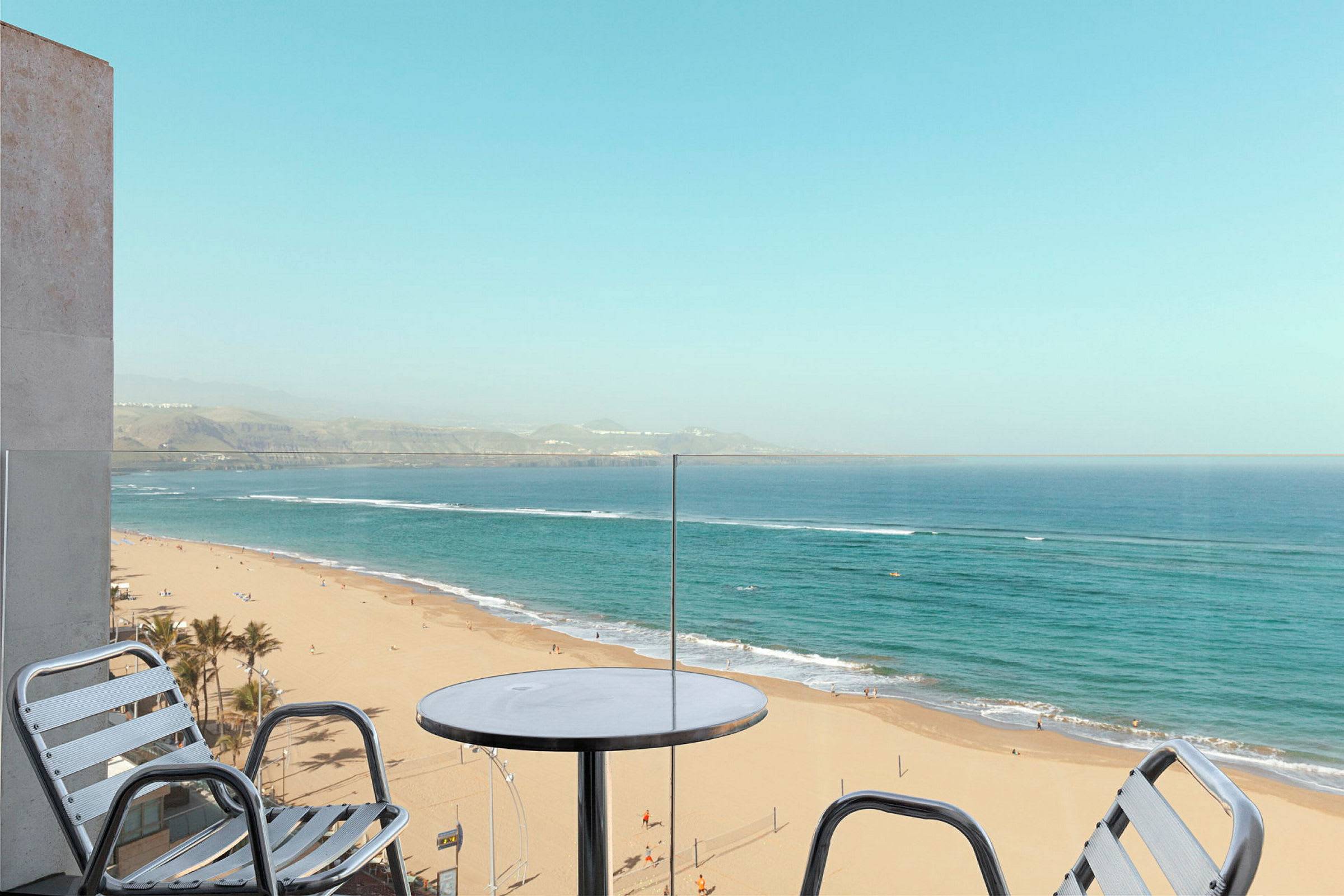 Udsigt fra en balkon mod en sandstrand og havet. (AI-genereret tekst)