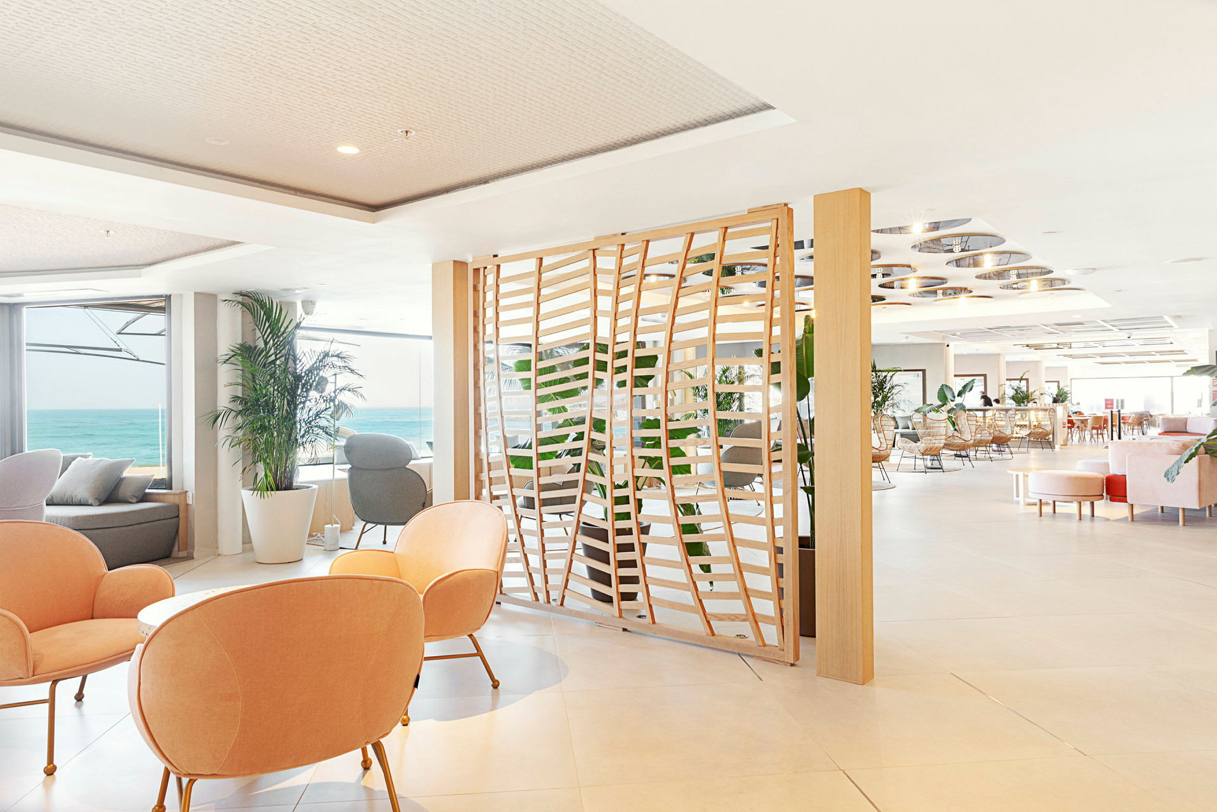 Lyst indrettet hotellounge med udsigt over havet. (AI-genereret tekst)