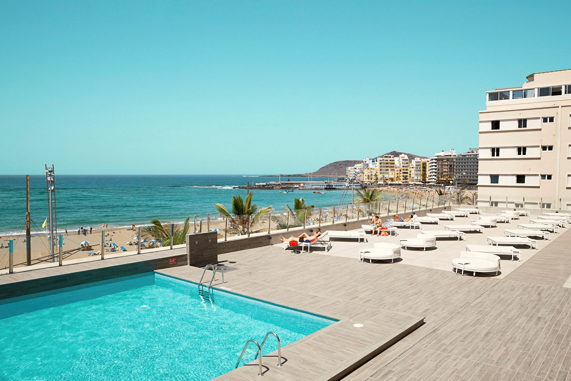 Udsigt over en pool og en strand med havet i baggrunden. (AI-genereret tekst)