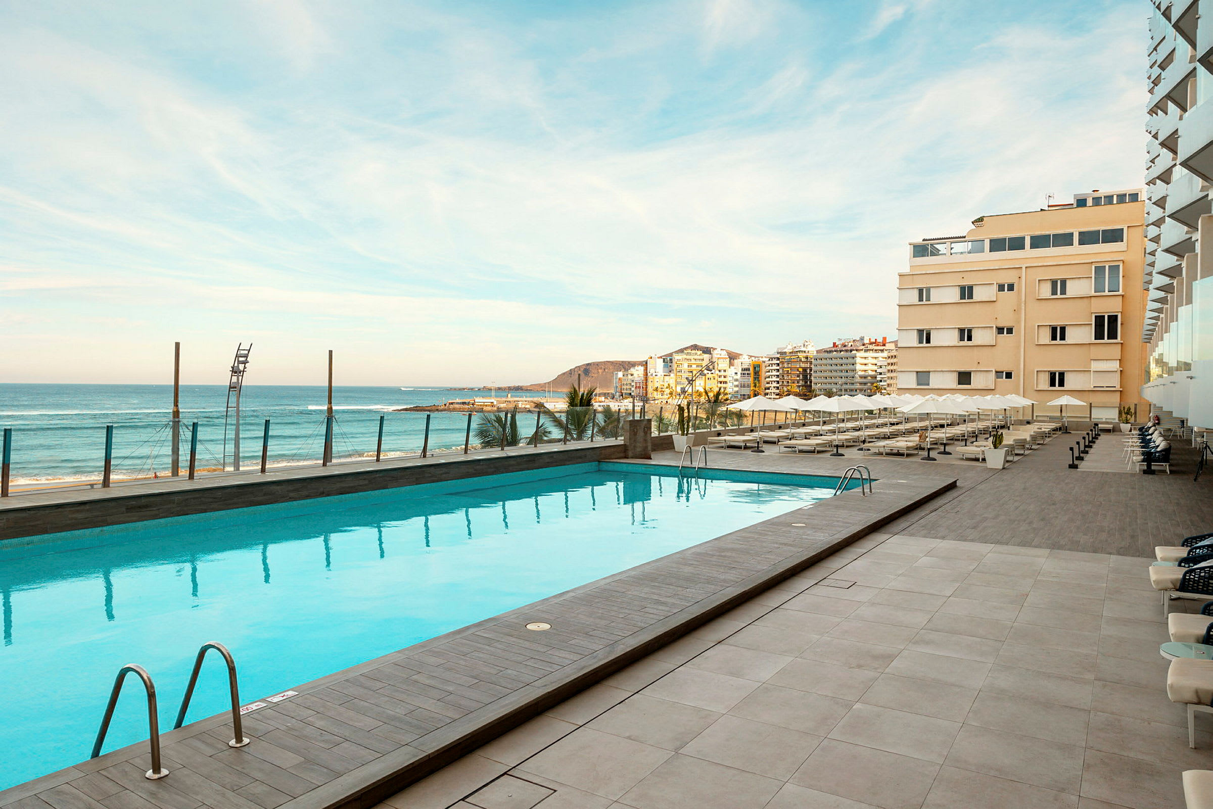 Udendørs pool ved hotellet med udsigt over stranden og havet. (AI-genereret tekst)