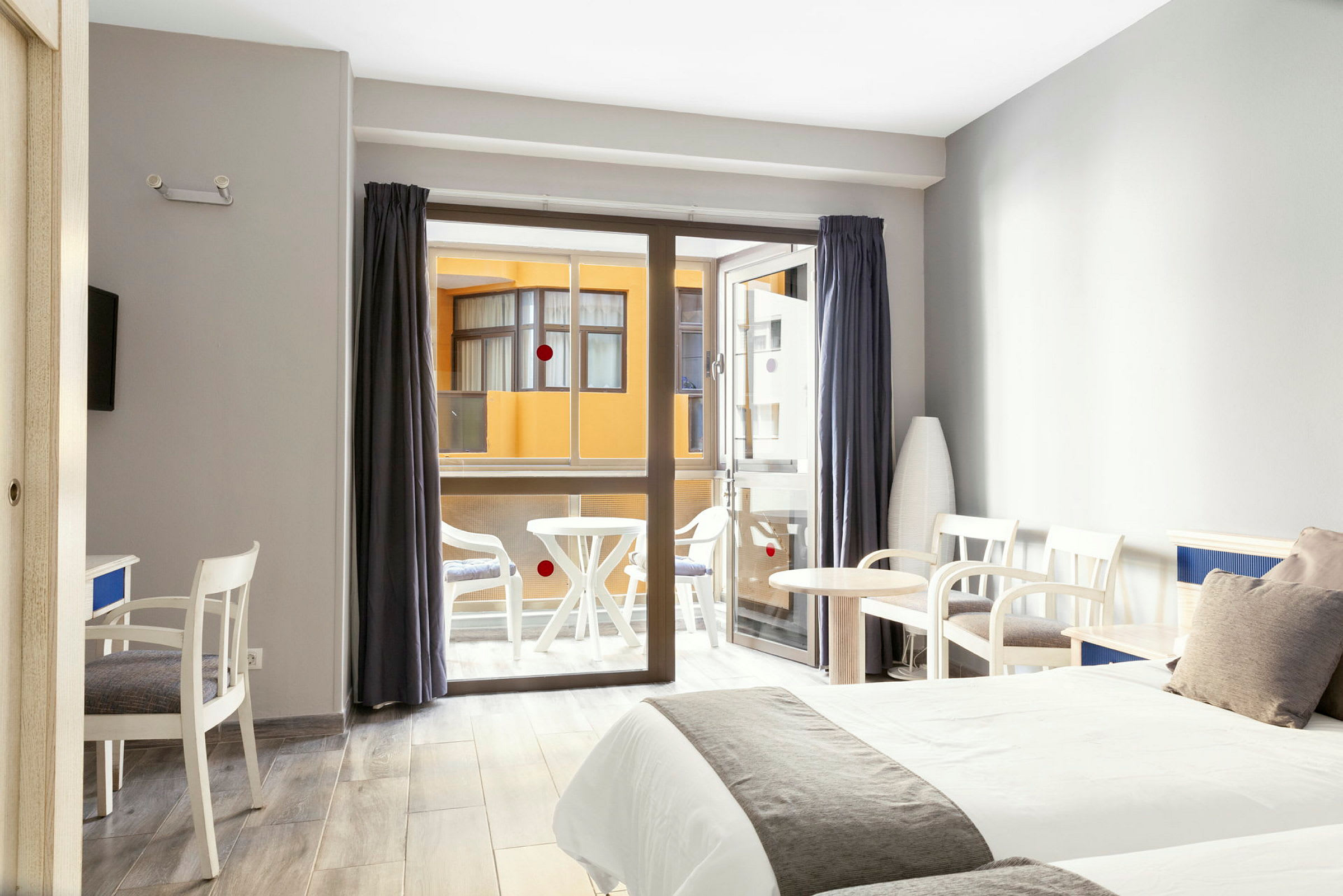 Hotelværelse med to senge, siddeområde og en balkon i baggrunden. (AI-genereret tekst)