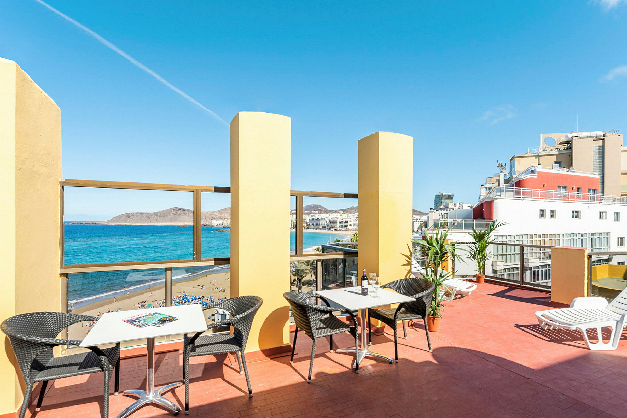 En terrasse med borde og stole, udsigt over havet og stranden. (AI-genereret tekst)