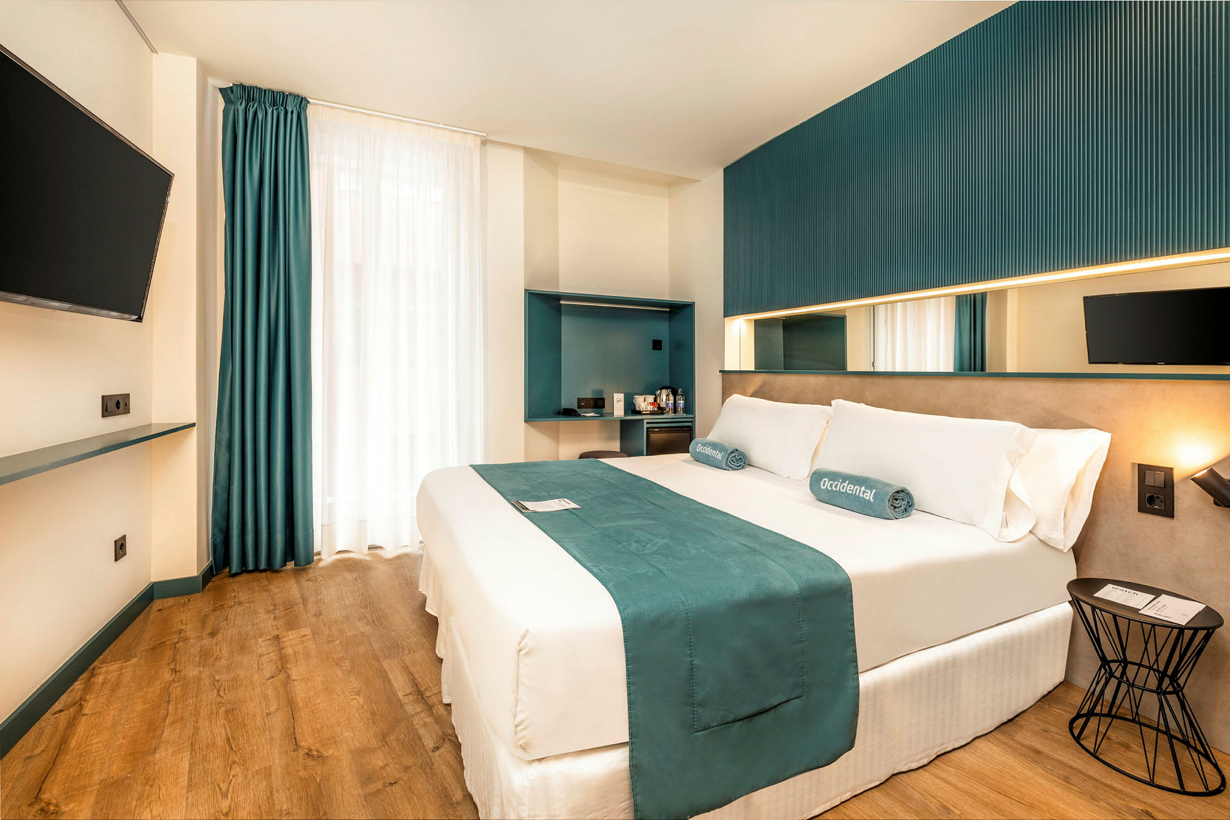 Et moderne hotelværelse med en dobbeltseng, vægmonteret TV og minimalistisk indretning. (AI-genereret tekst)