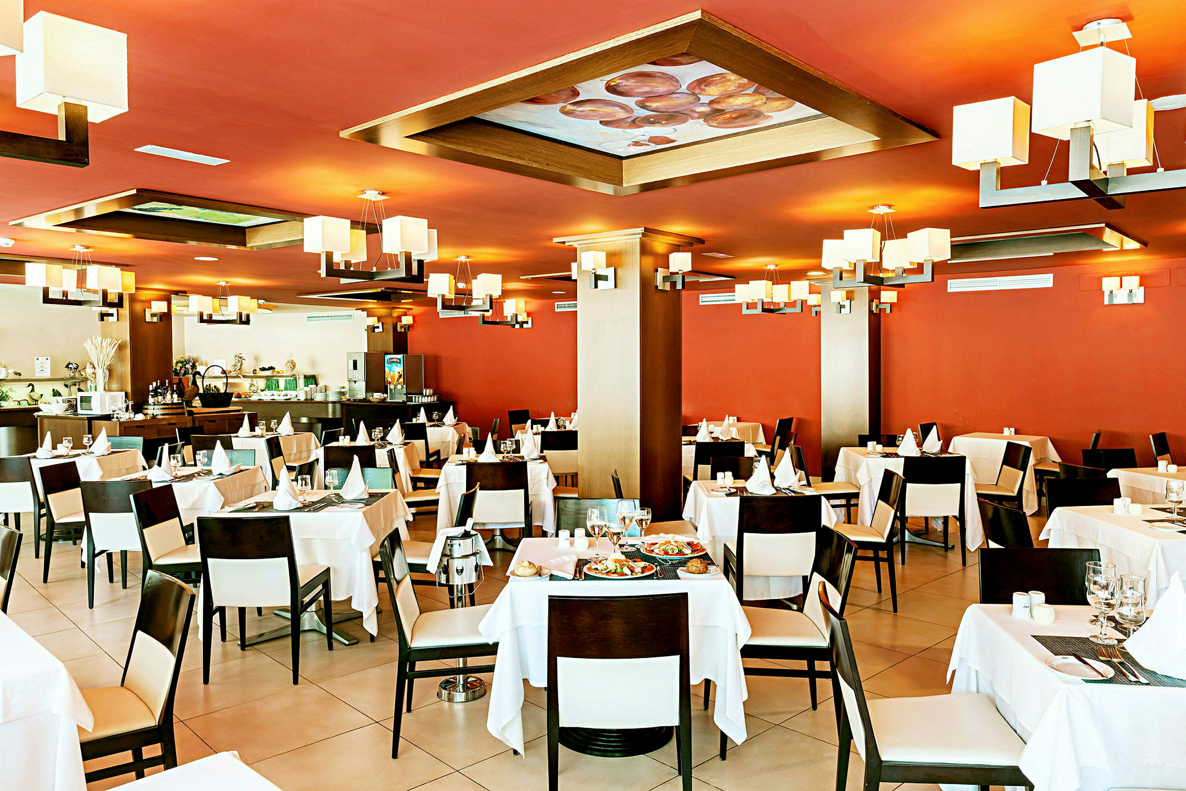 Interiør af en restaurant med røde vægge, hvide duge og moderne belysning. (AI-genereret tekst)