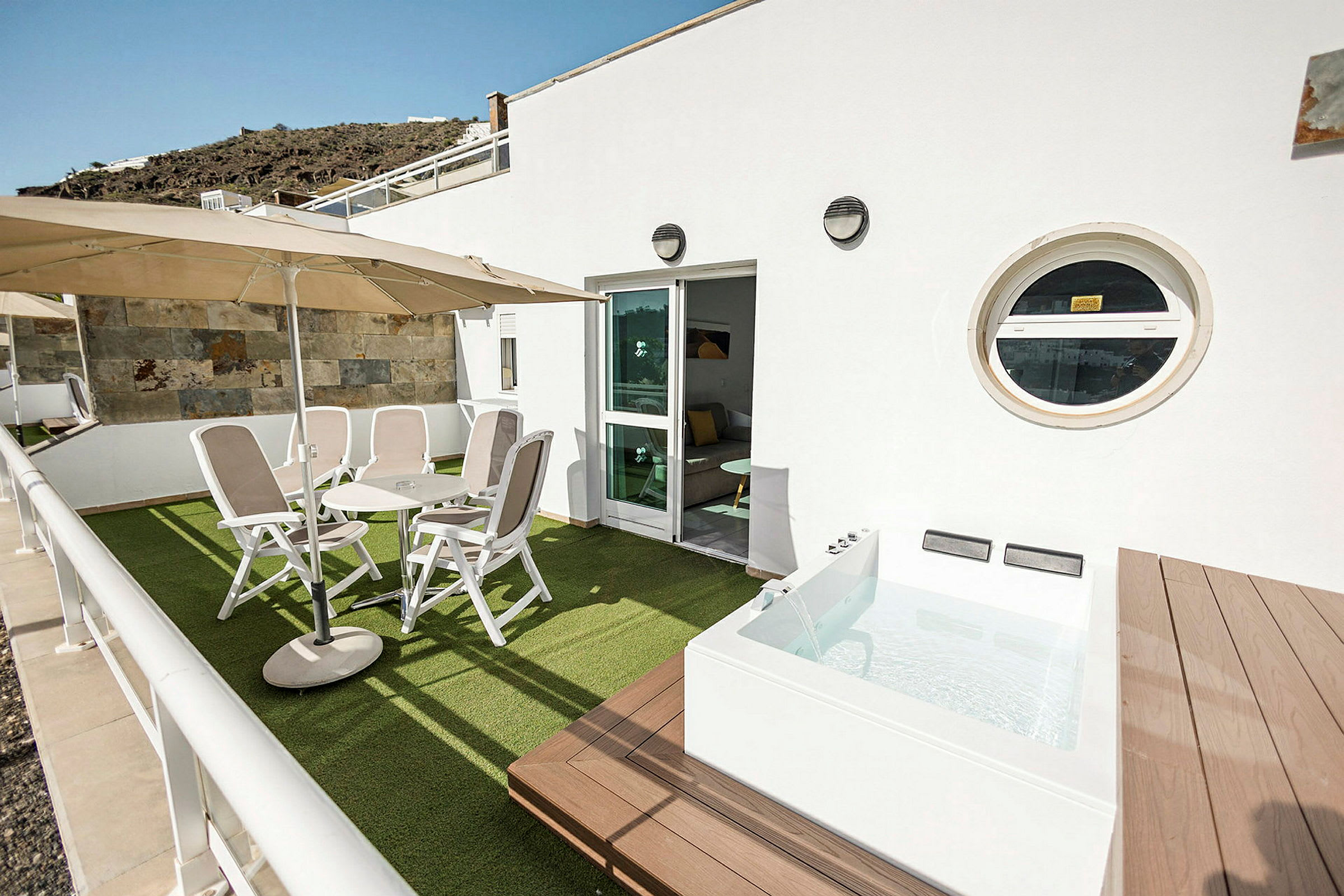 Terrasse med stole, bord og en lille pool. (AI-genereret tekst)
