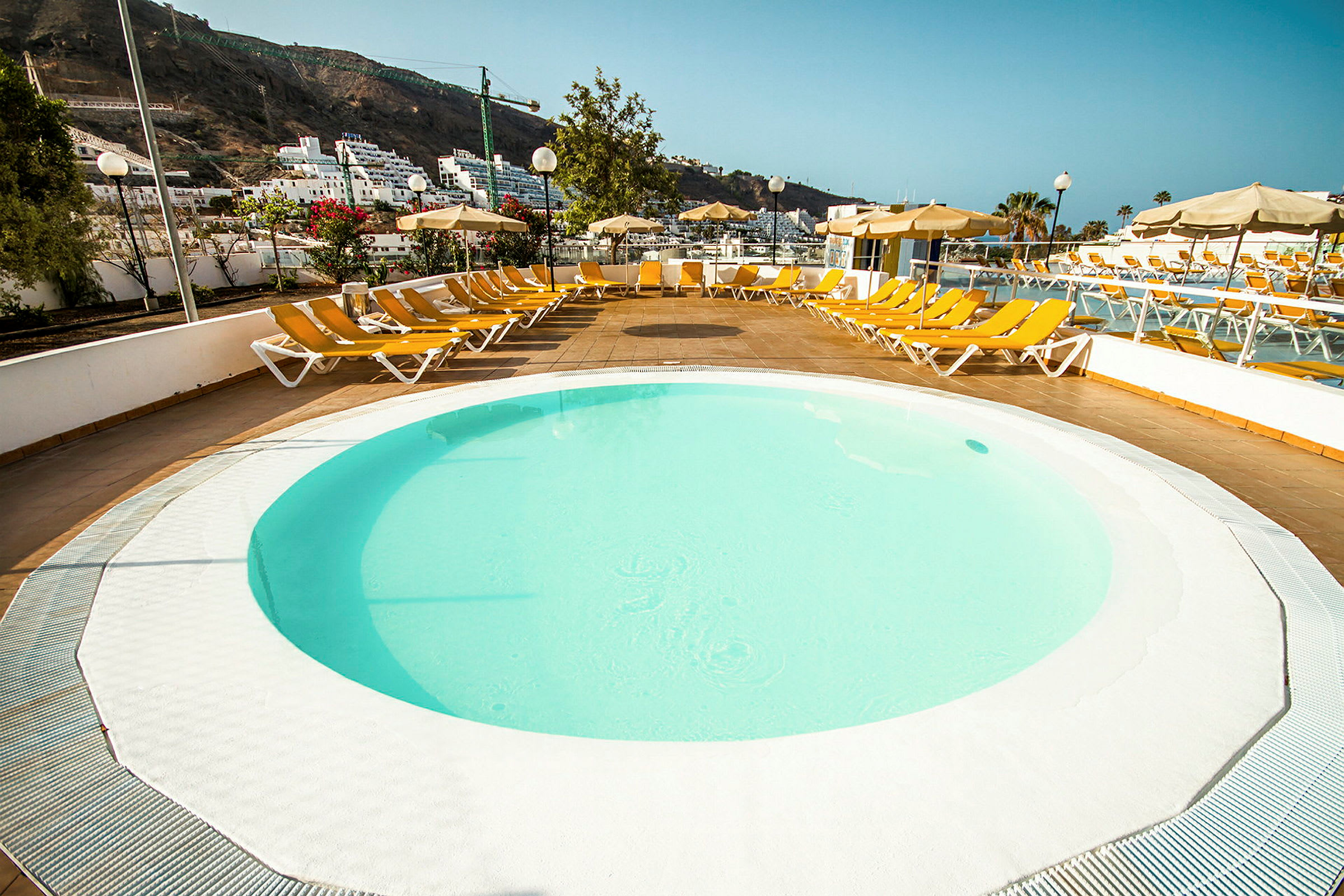 Rund pool med solsenge omkring. (AI-genereret tekst)