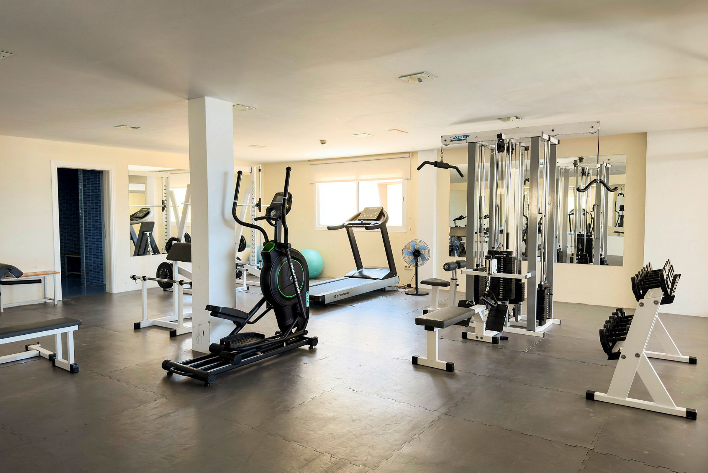 Et fitnesscenter med træningsudstyr såsom løbebånd, elliptisk træningsmaskine, styrketræningsmaskiner og håndvægte. (AI-genereret tekst)