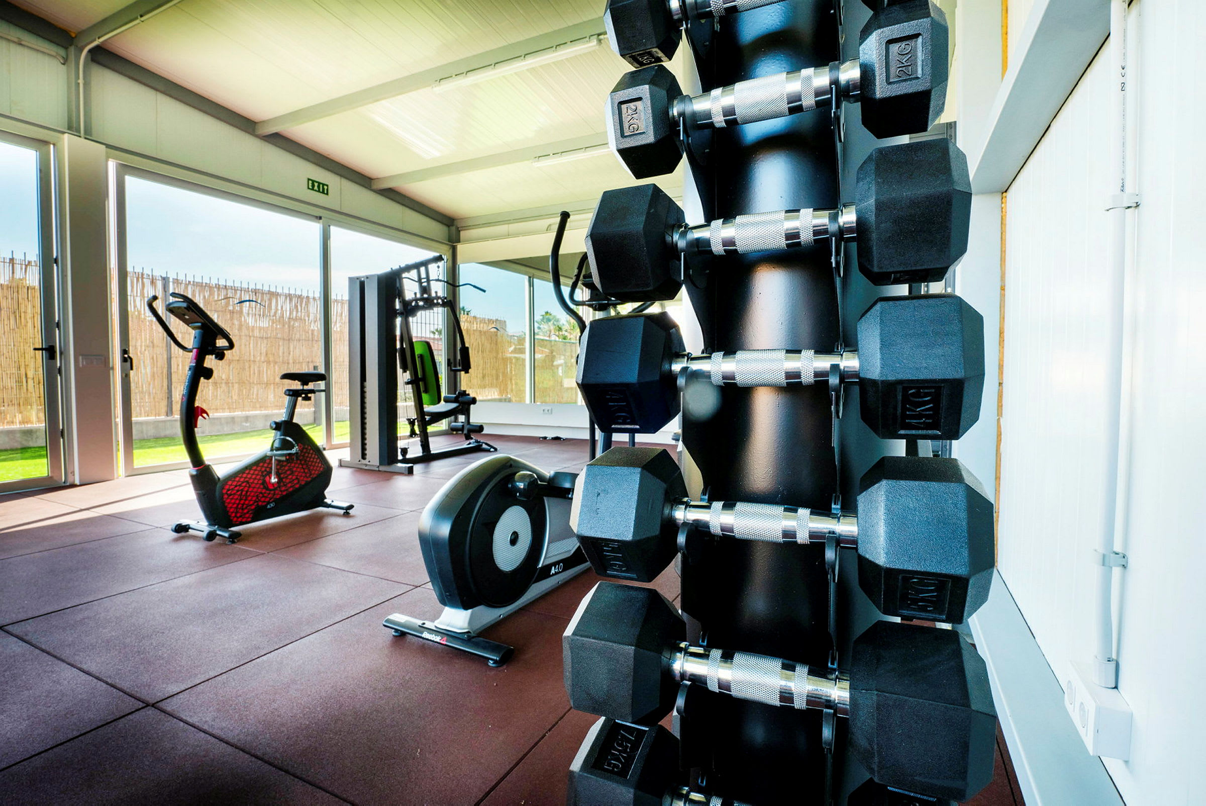 Et fitnessrum med træningsudstyr, herunder håndvægte, motionscykel og maskiner. (AI-genereret tekst)