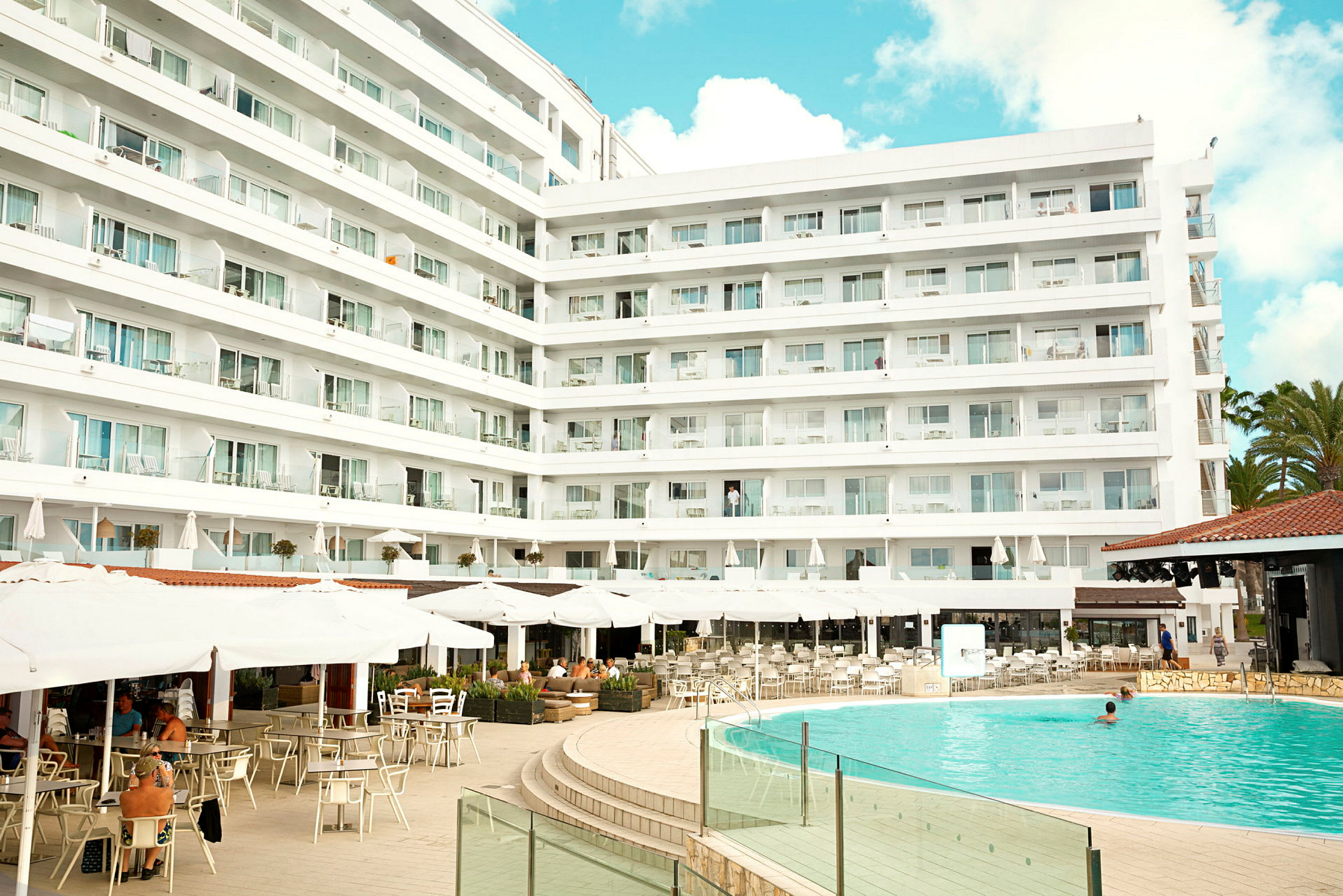Hotelkompleks med pool og udendørs servering. (AI-genereret tekst)