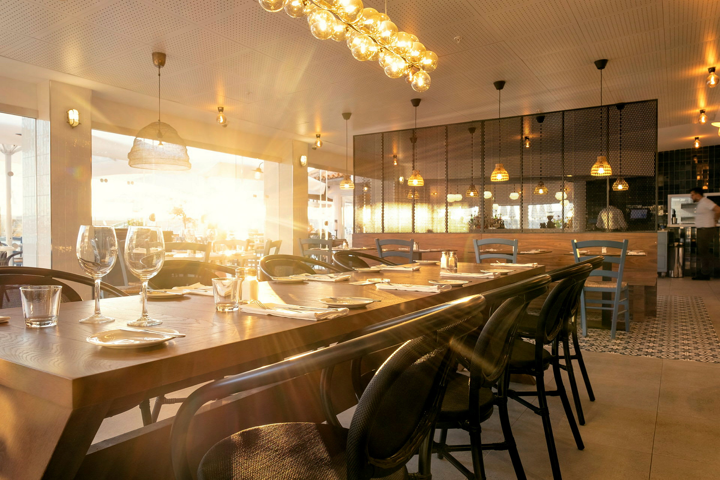 En stemningsfuld restaurant med borde dækket til gæster og varm belysning. (AI-genereret tekst)