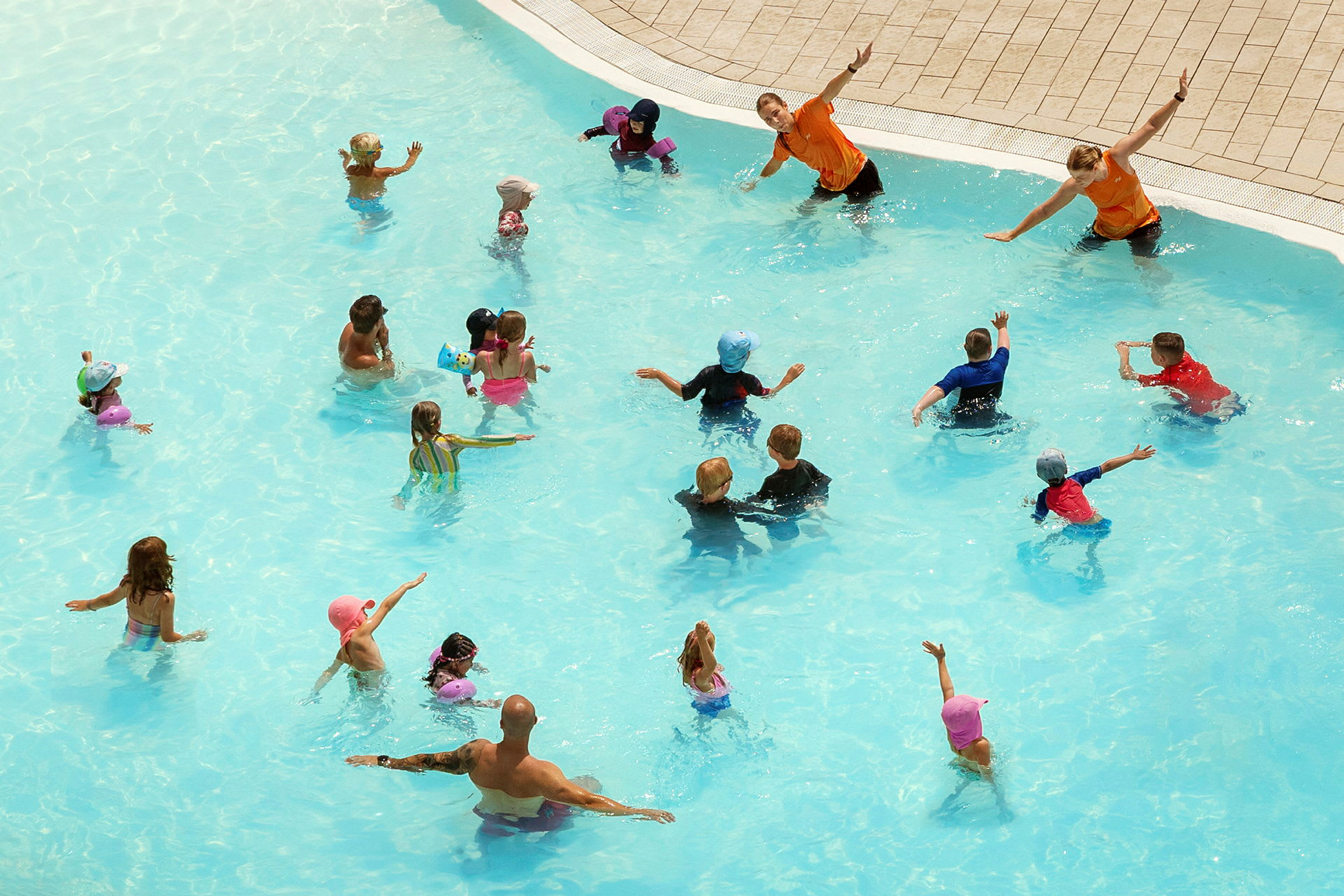 Personer leger og deltager i aktiviteter i en swimmingpool. (AI-genereret tekst)
