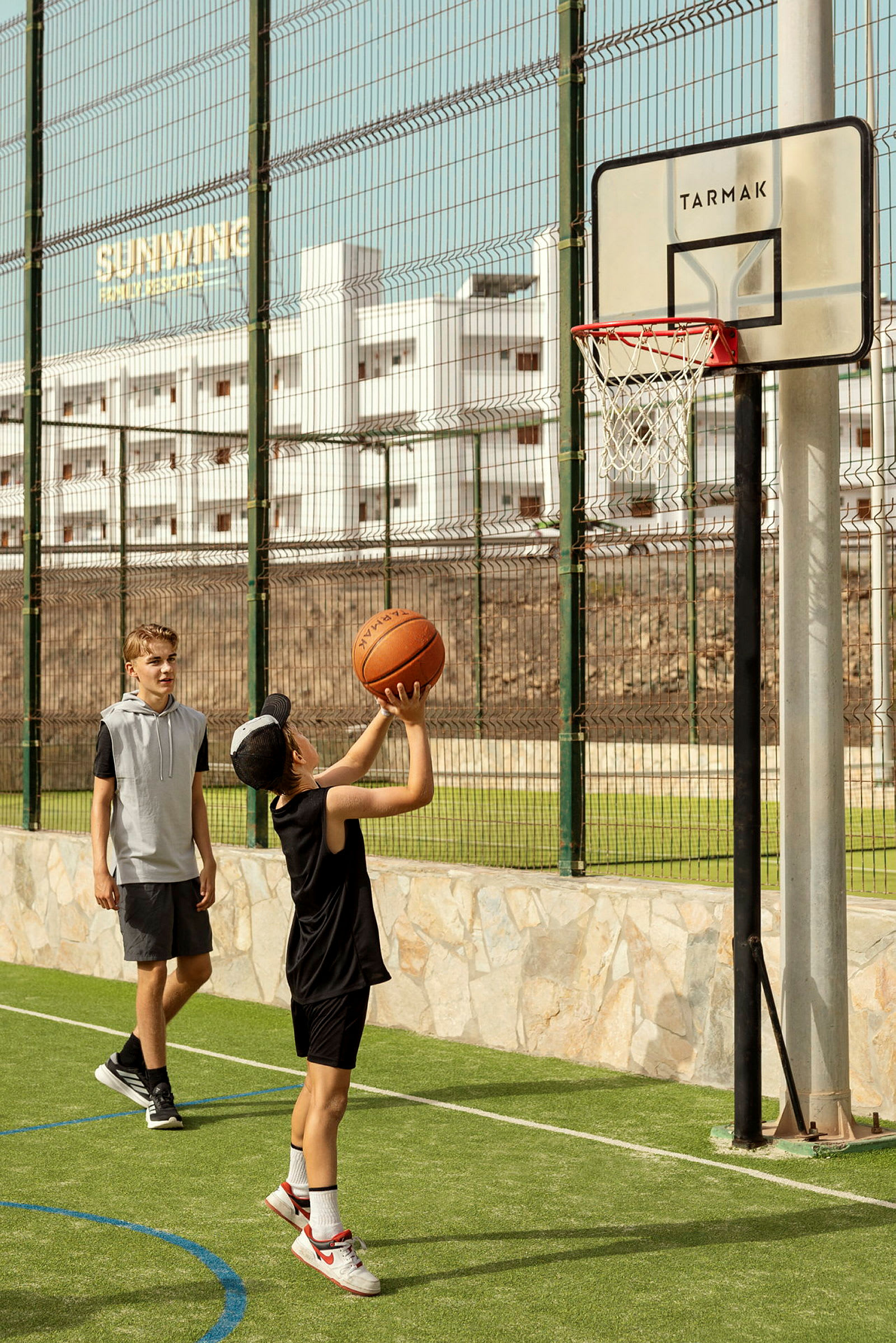 En person spiller basketball udendørs mod et net med en bold. (AI-genereret tekst)