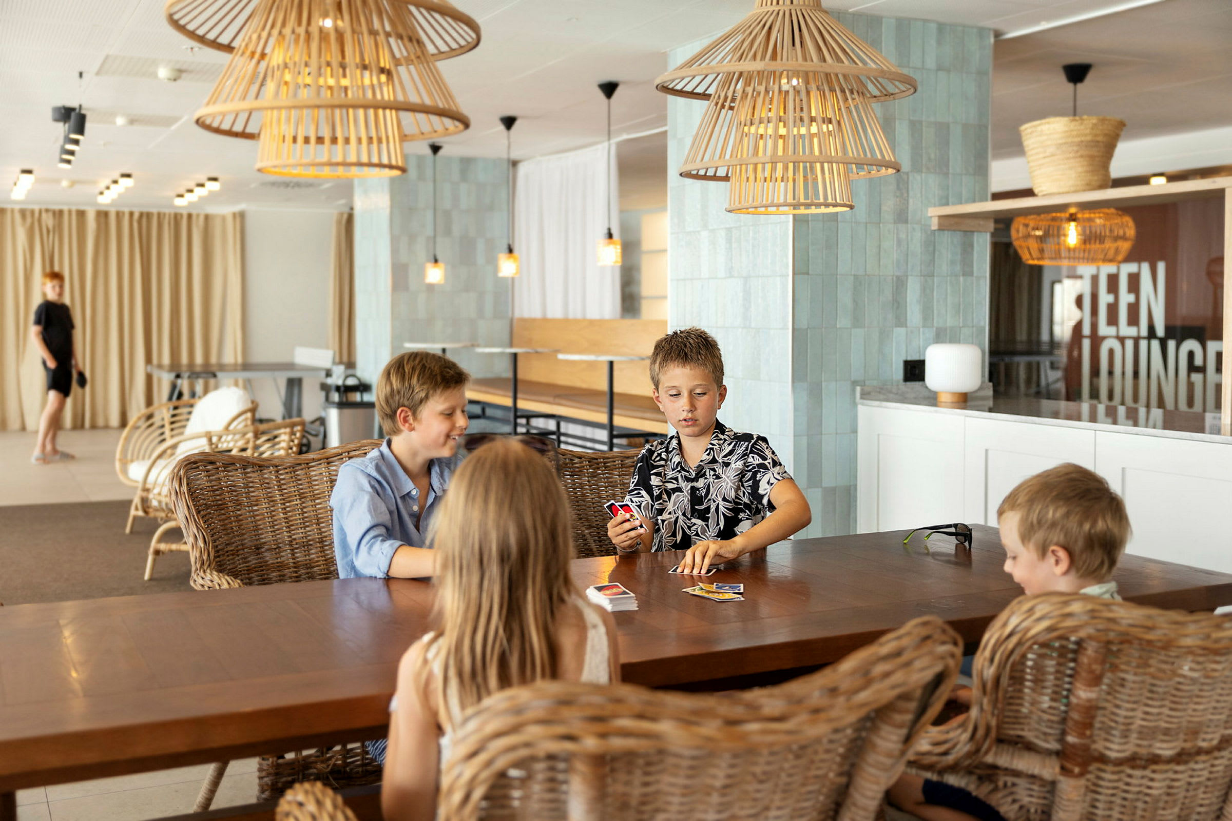 Fire personer sidder ved et bord og spiller kort i en moderne lounge. (AI-genereret tekst)