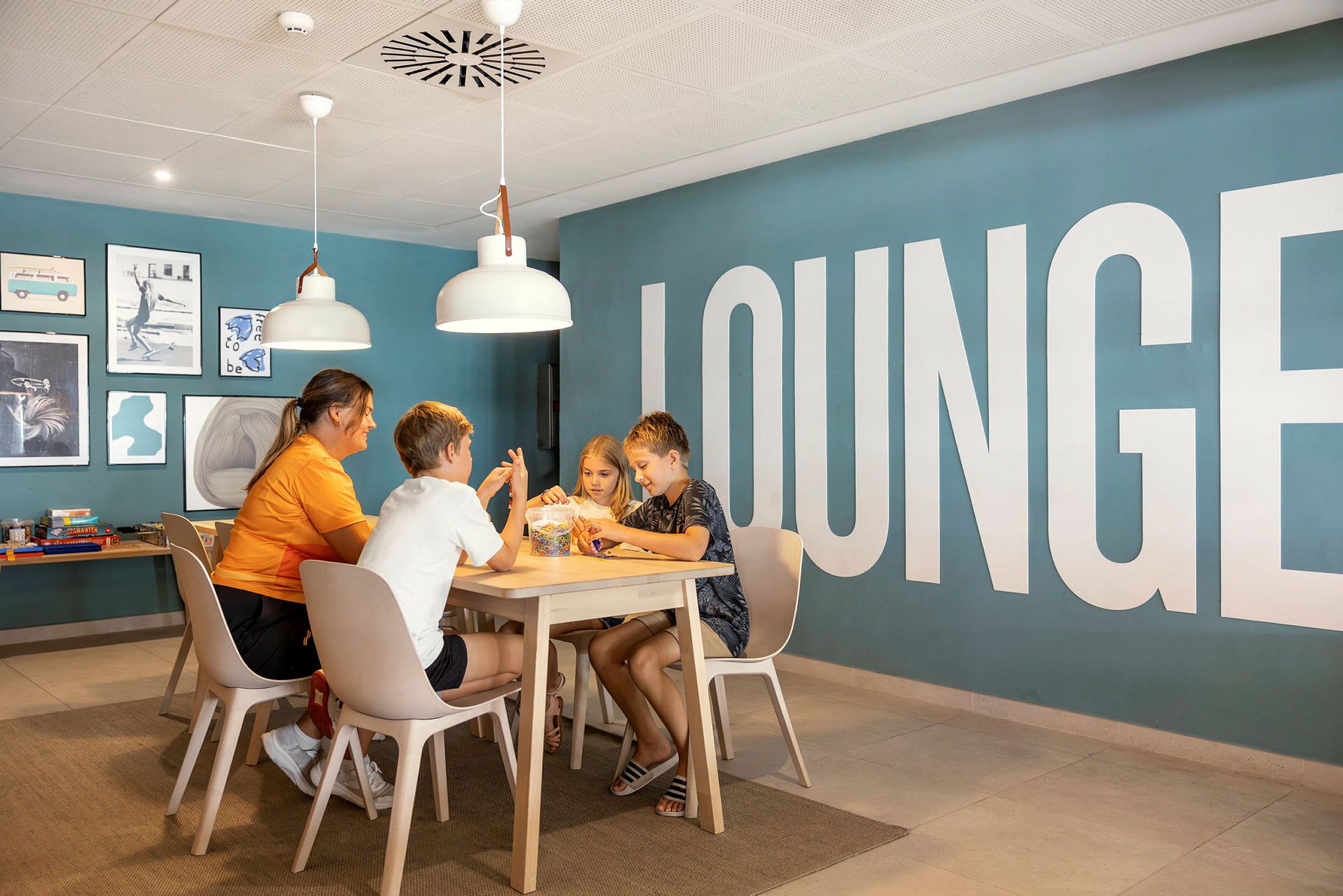 En gruppe mennesker sidder ved et bord i en lounge med blå vægge og dekorativ kunst. (AI-genereret tekst)