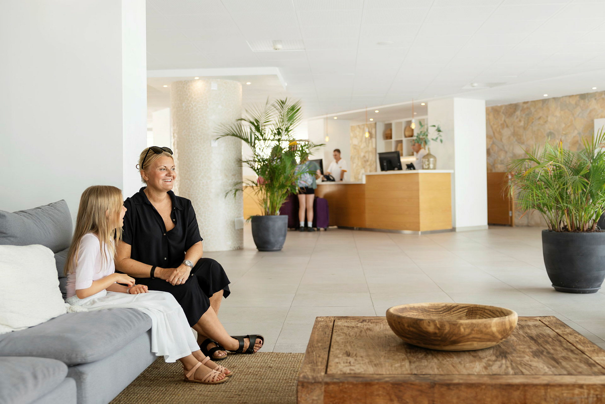 Hotellobby med sofaer, bord og reception. (AI-genereret tekst)