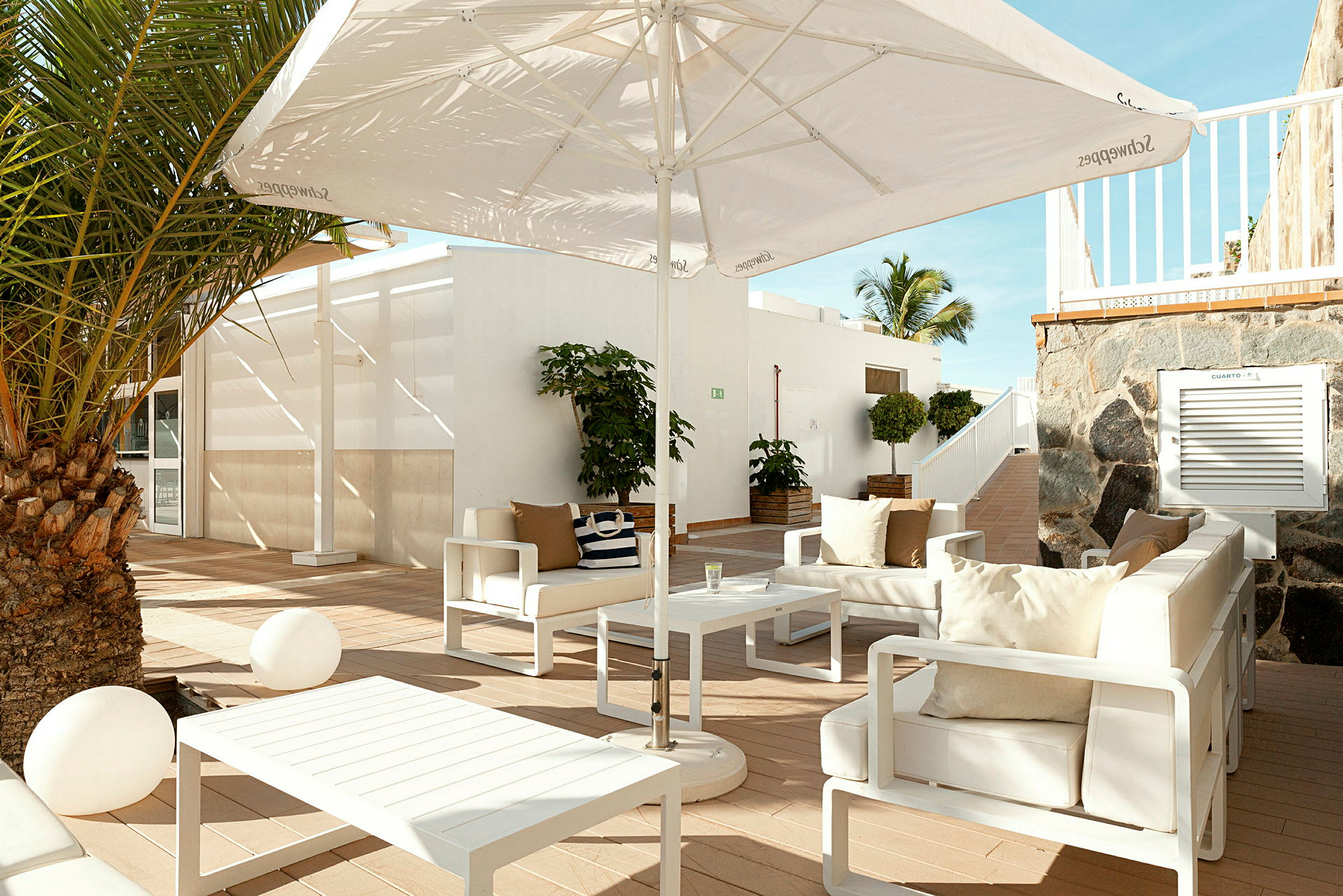Udendørs loungemøbler med sofaer, parasol og et bord på en terrasse. (AI-genereret tekst)