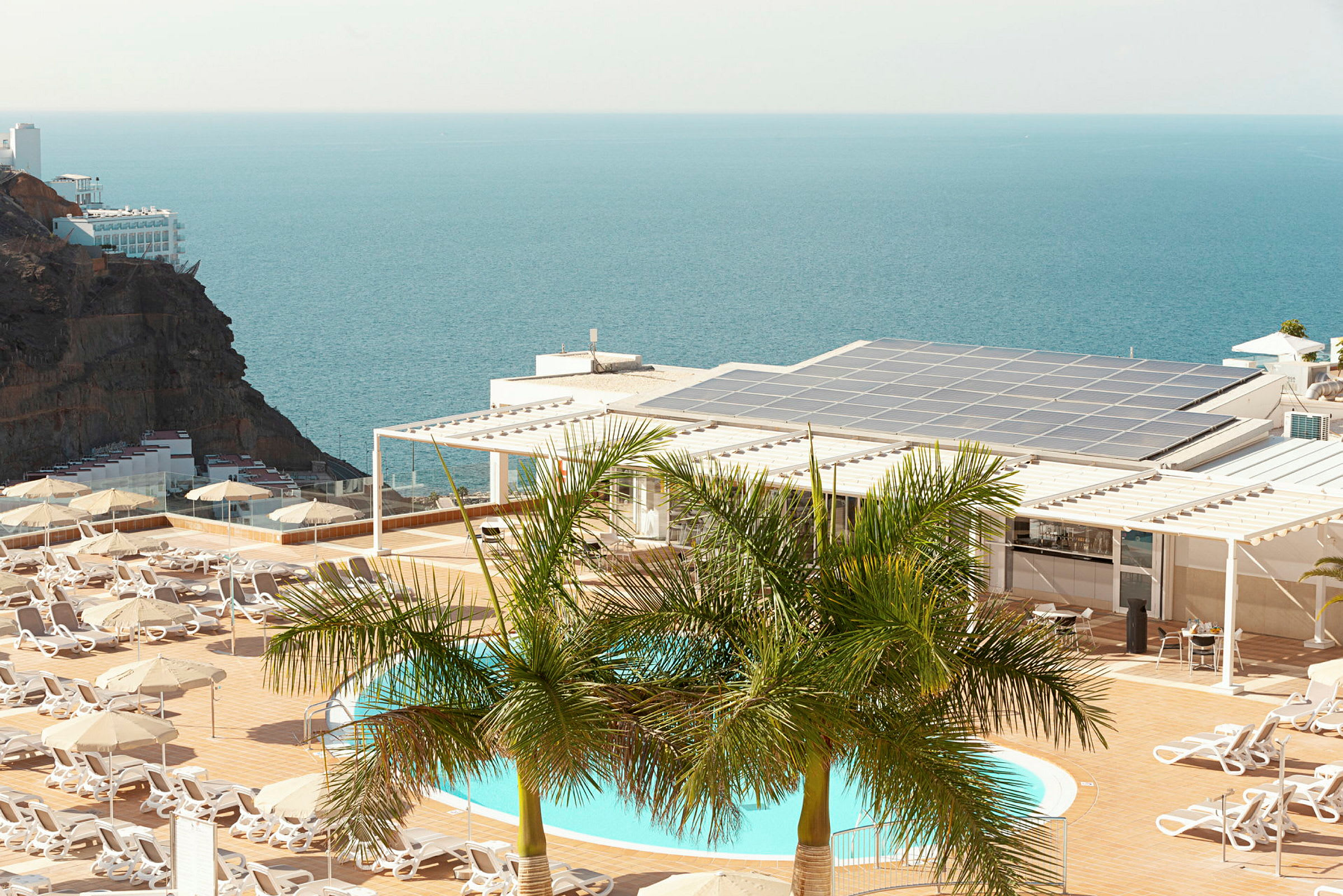 En pool og liggestole på en terrasse med udsigt over havet. (AI-genereret tekst)