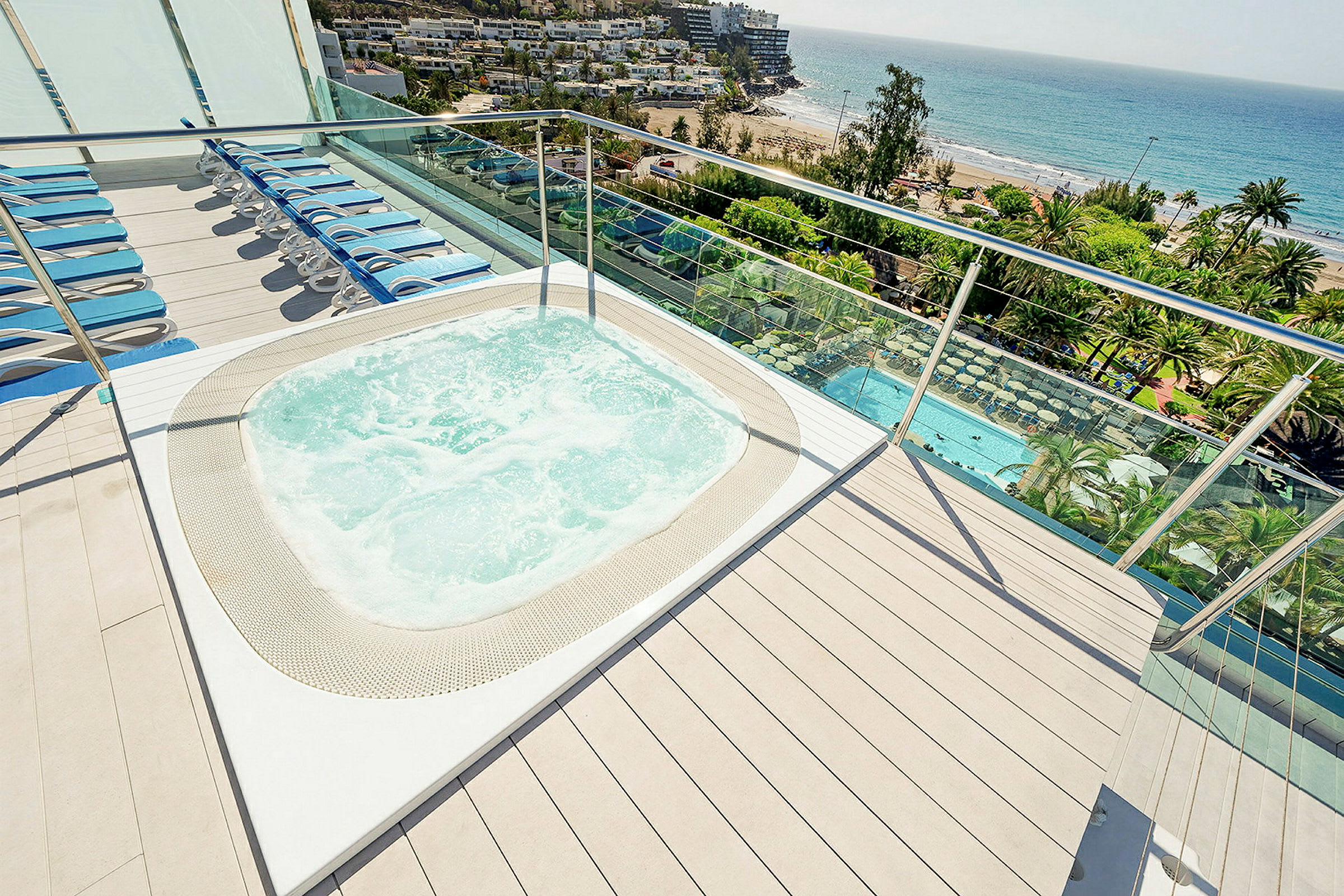Jacuzzi og liggestole på en terrasse med udsigt over havet. (AI-genereret tekst)