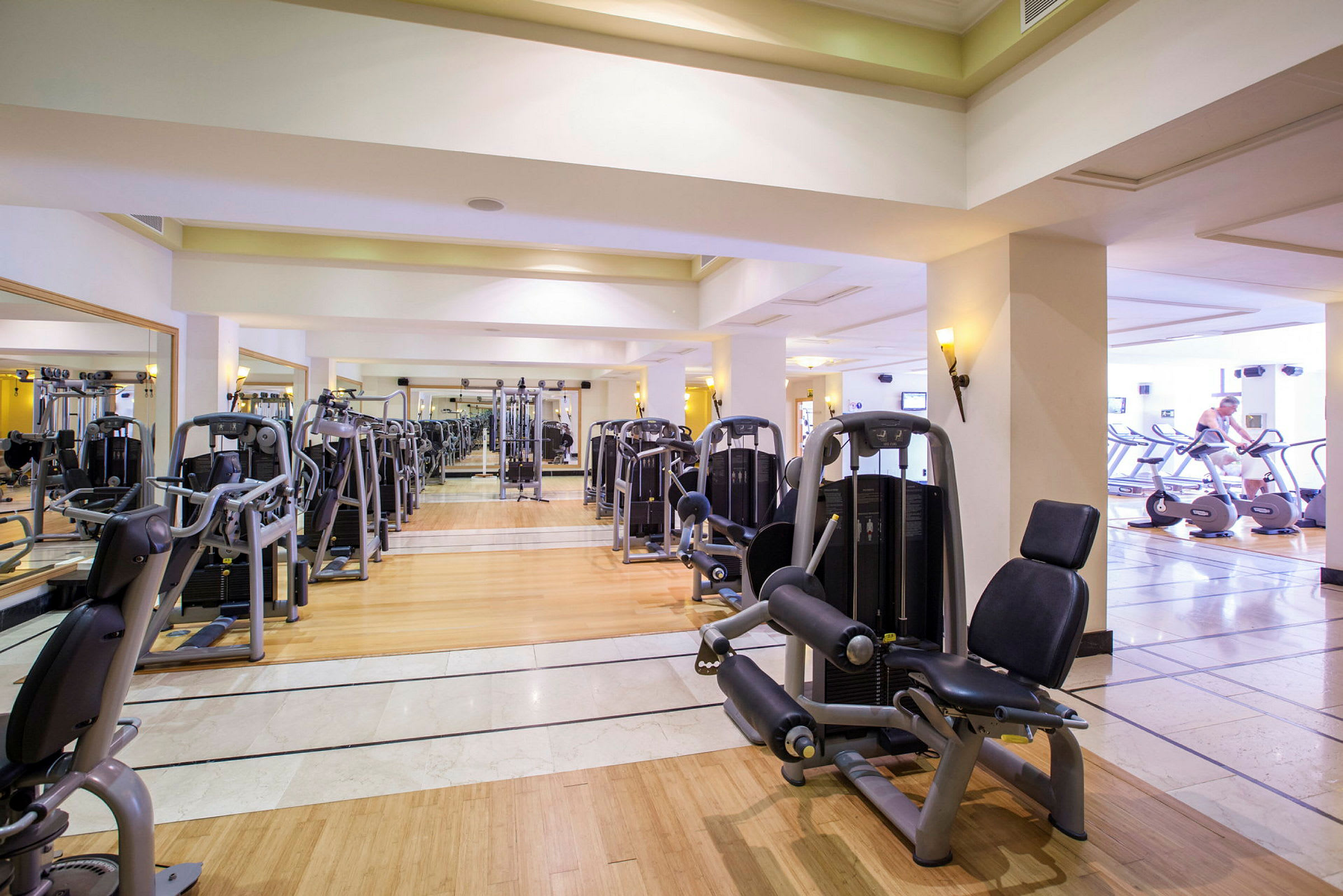 Billede af et fitnesscenter med træningsmaskiner og spejle på væggene. (AI-genereret tekst)