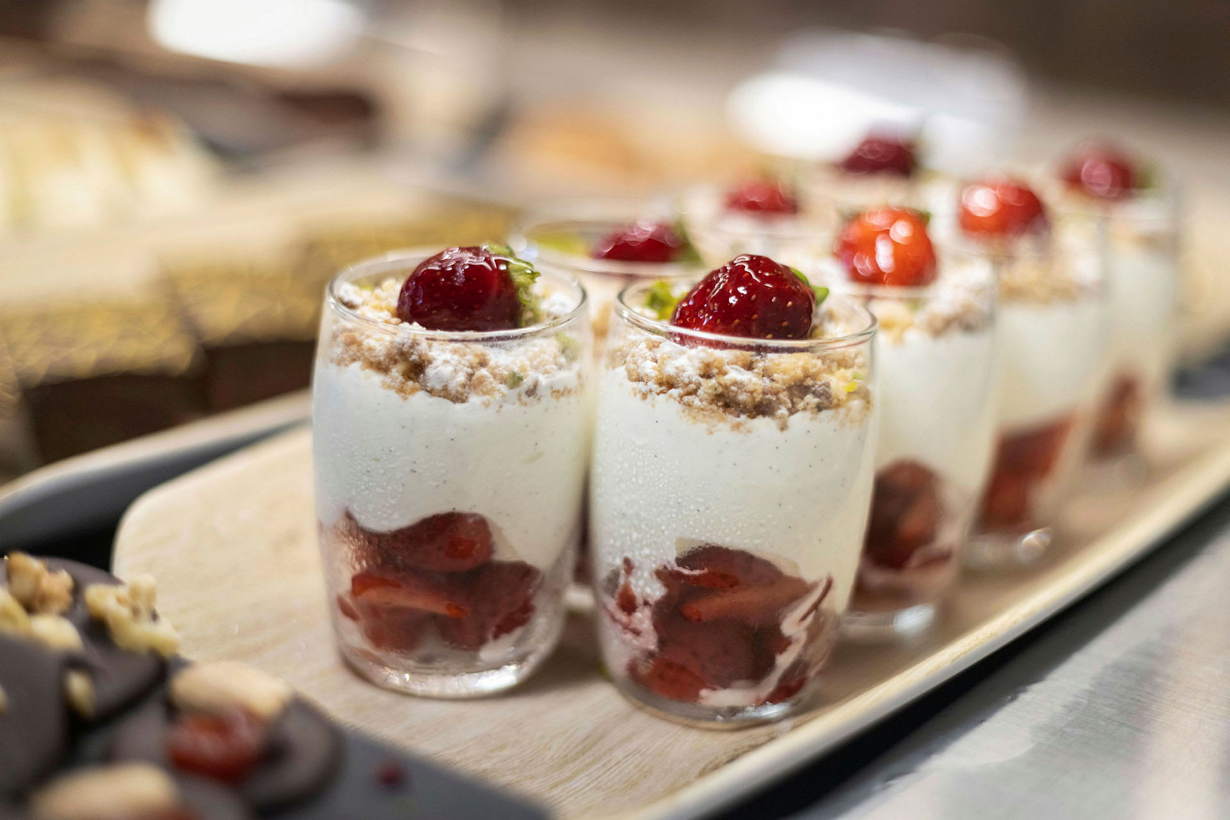 Glas med dessert bestående af jordbær, fløde og krummer. (AI-genereret tekst)