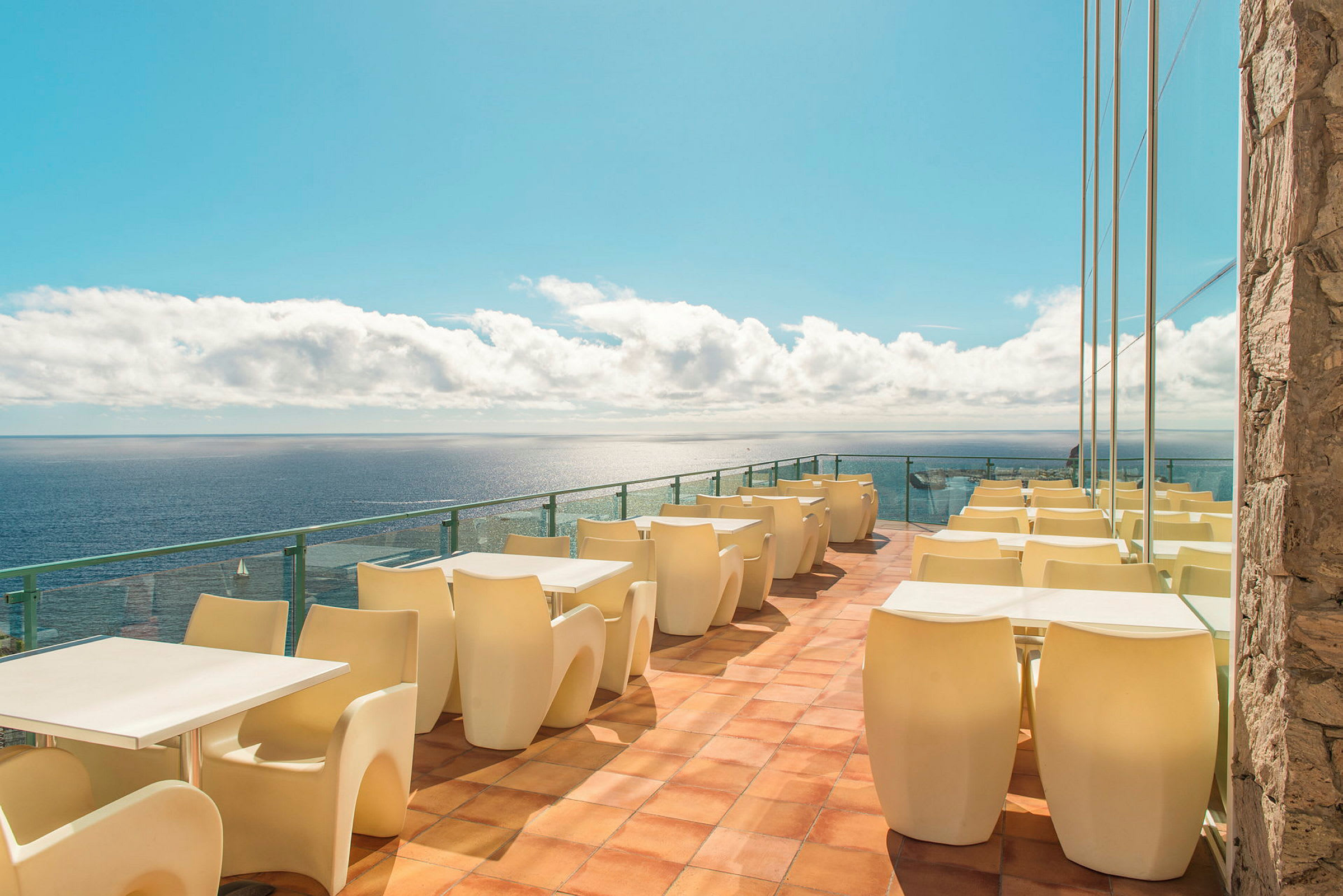 Terrasse med borde og stole ved havet. (AI-genereret tekst)