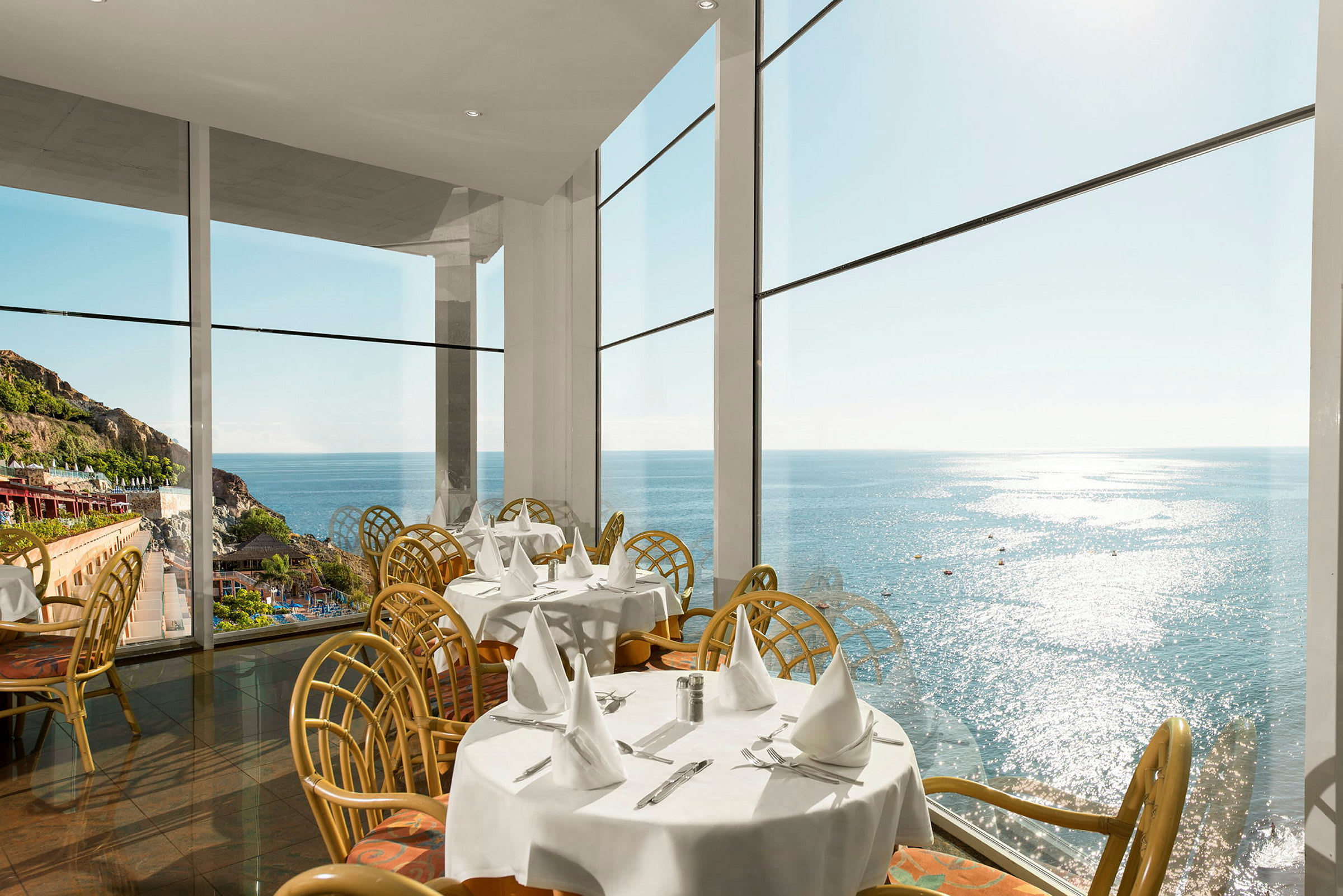 Restaurant med store vinduer og udsigt til havet. (AI-genereret tekst)
