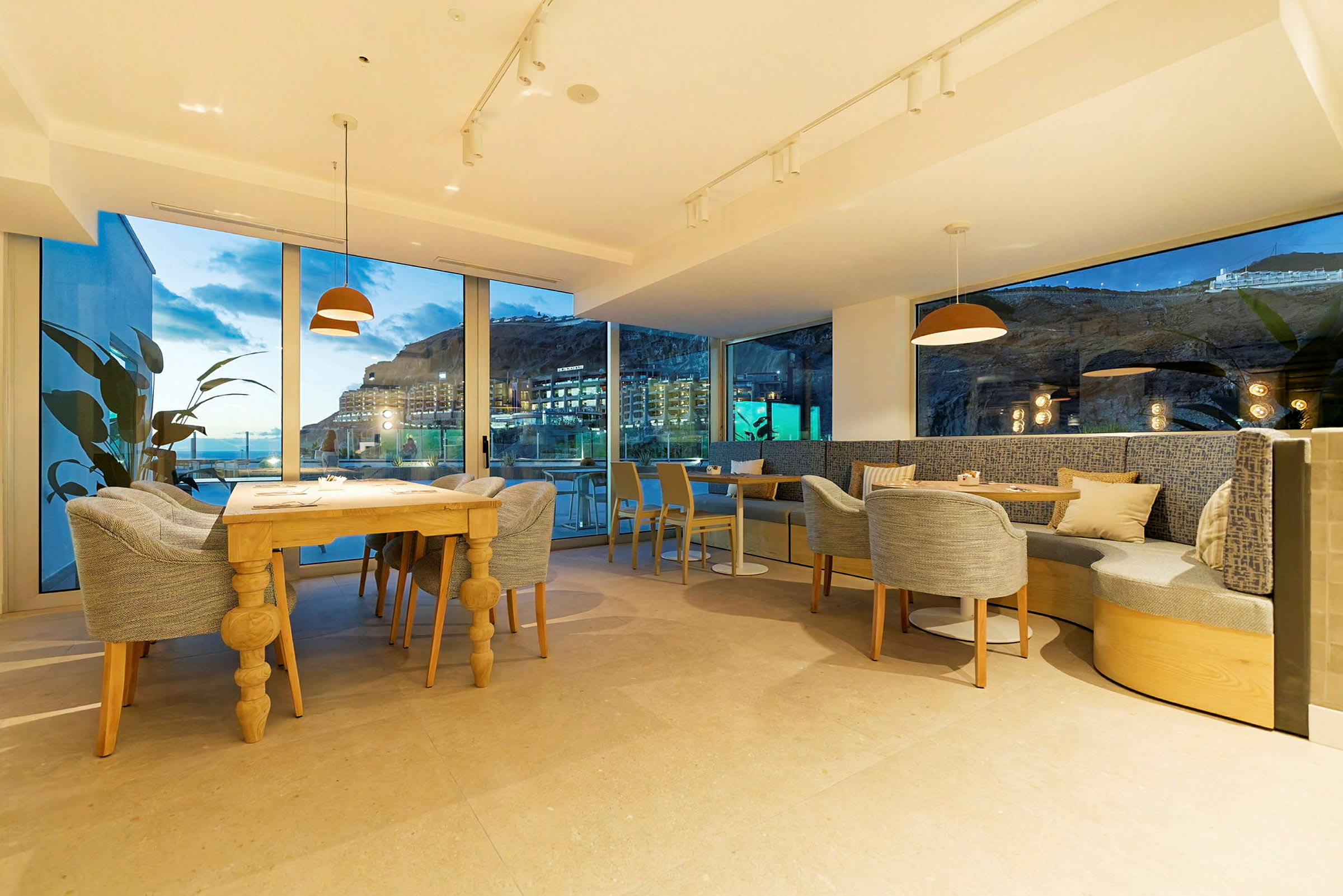Billede af en moderne restaurant med store vinduer og udsigt til aftenlandskabet. (AI-genereret tekst)