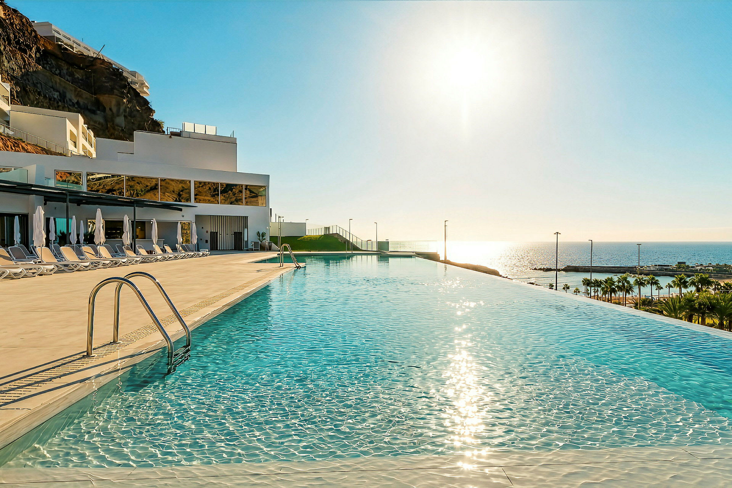 En infinity-pool med udsigt over havet og en solrig himmel. (AI-genereret tekst)
