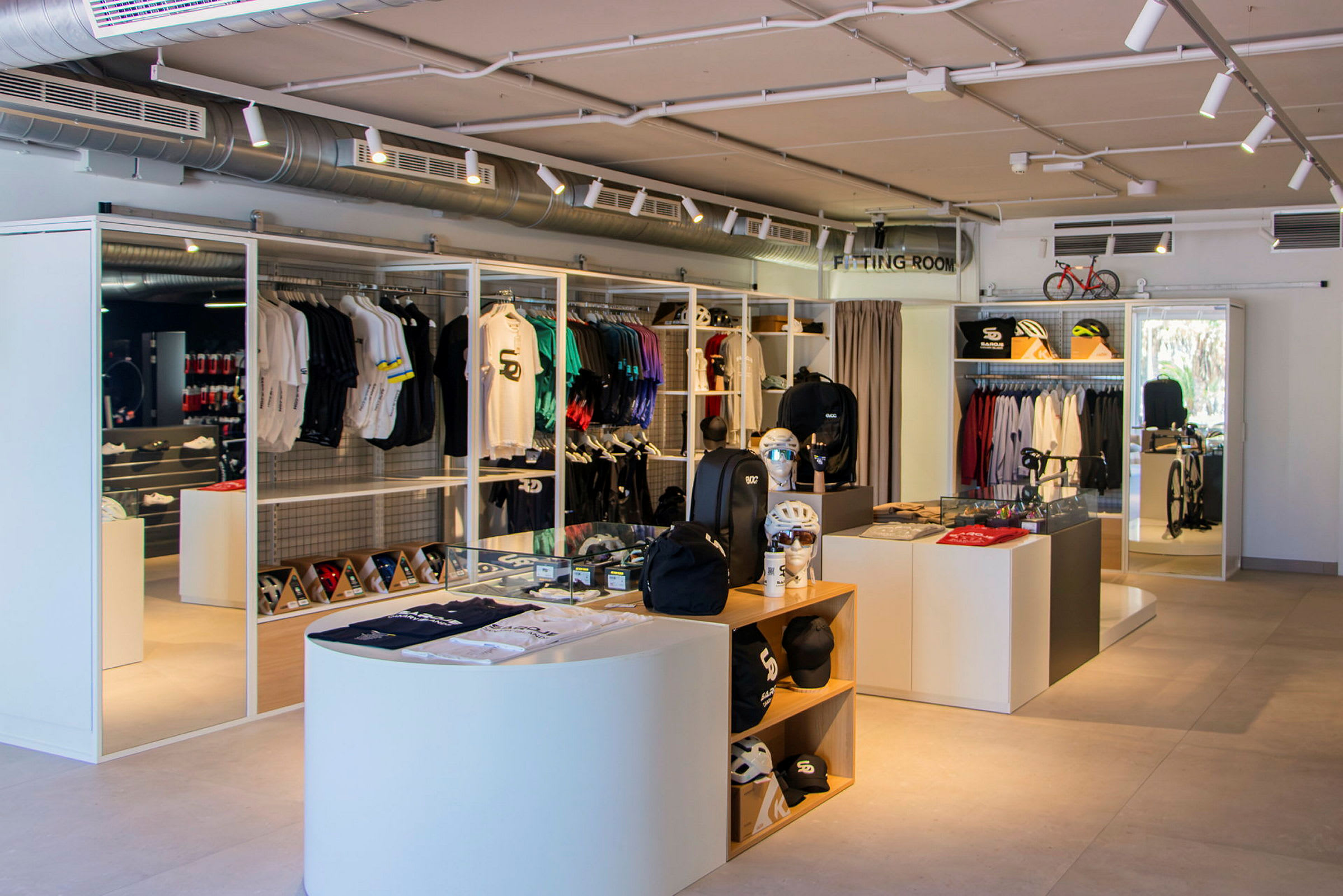 Interiør af en butik med sportstøj og udstyr, inklusive hjelme, rygsække og cykeltøj. (AI-genereret tekst)