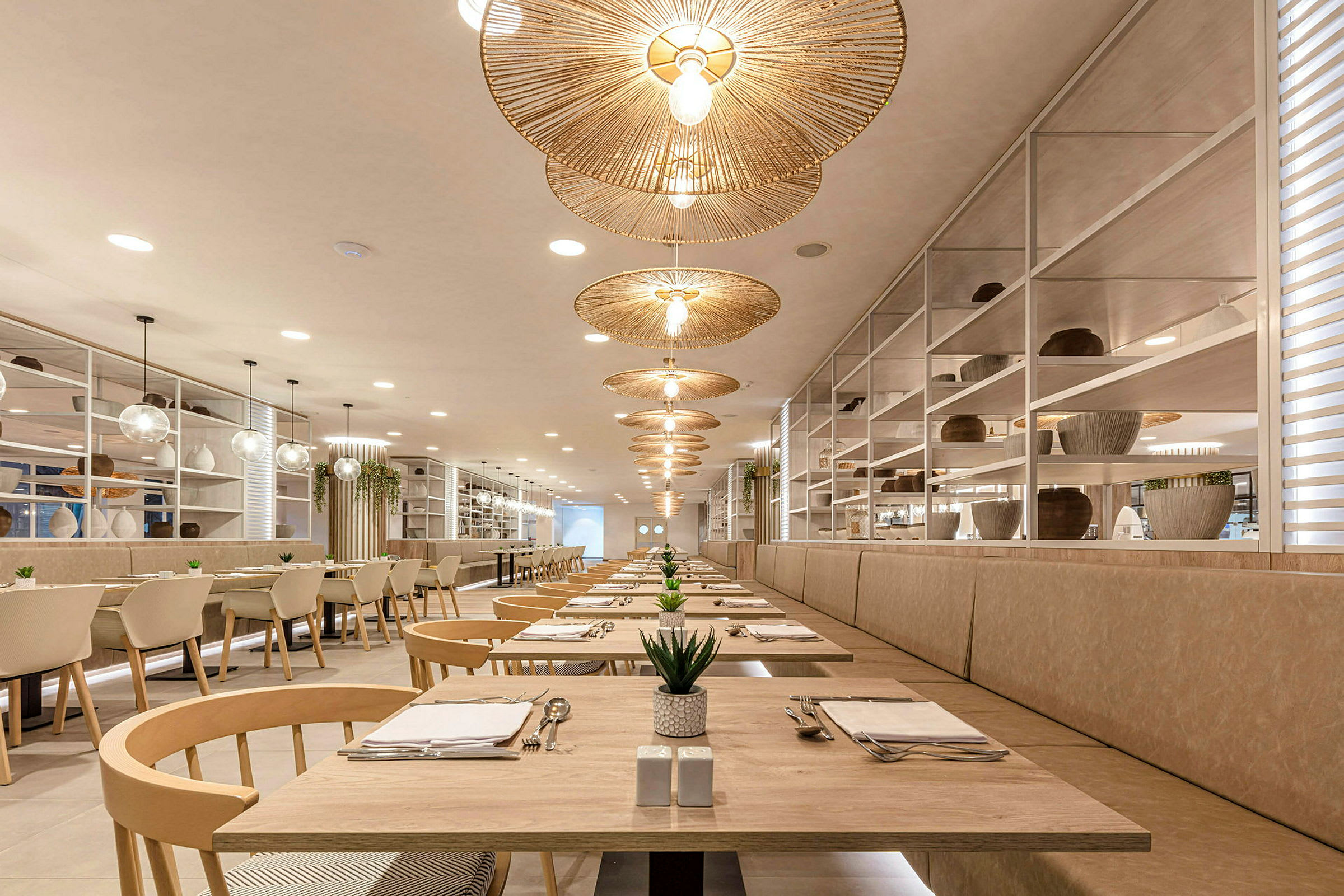 Luftig restaurant med elegante træborde, runde rottinglamper og plantepynt. (AI-genereret tekst)