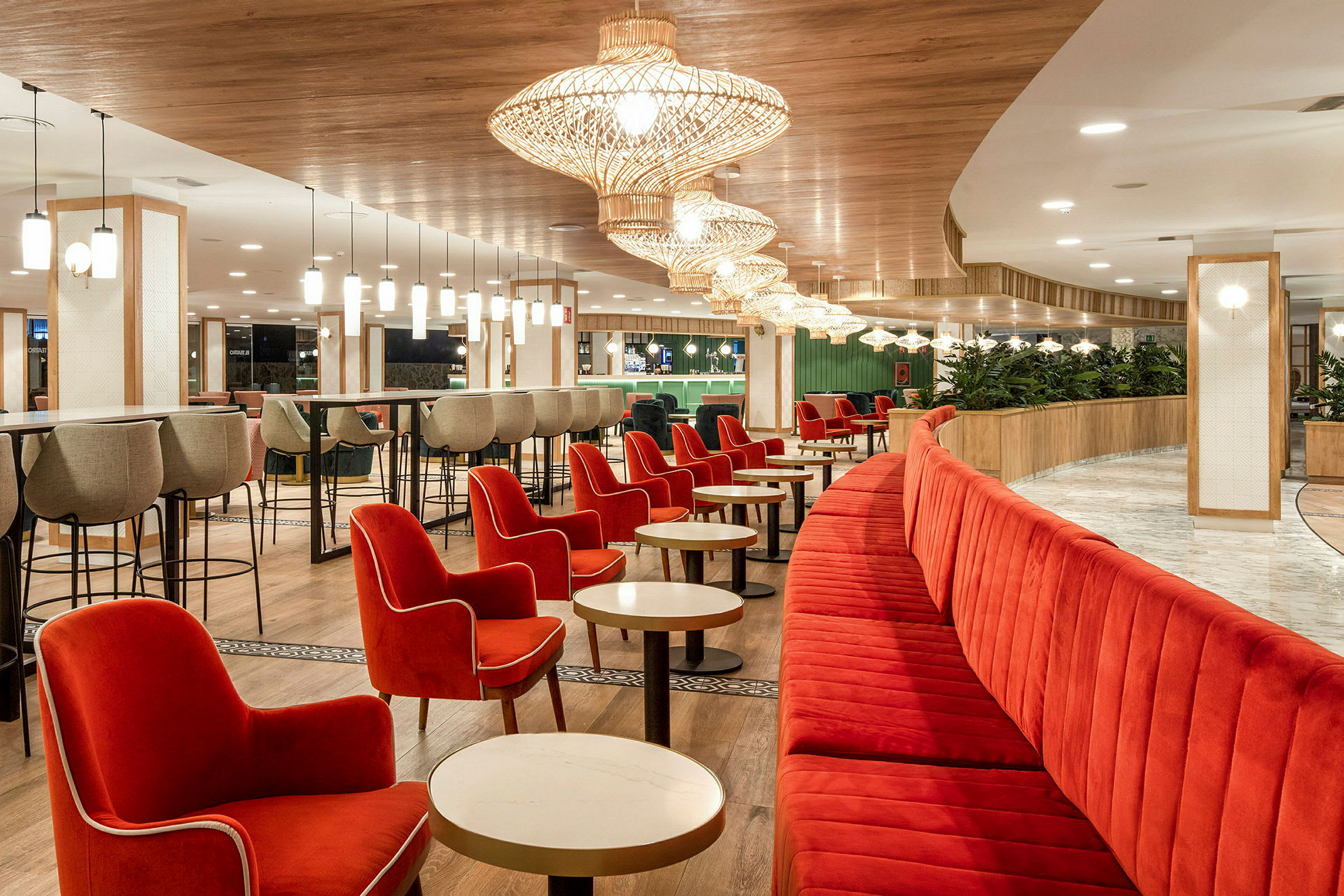 En restaurant med røde lænestole og bænke, lyse borde og moderne loftslamper. (AI-genereret tekst)