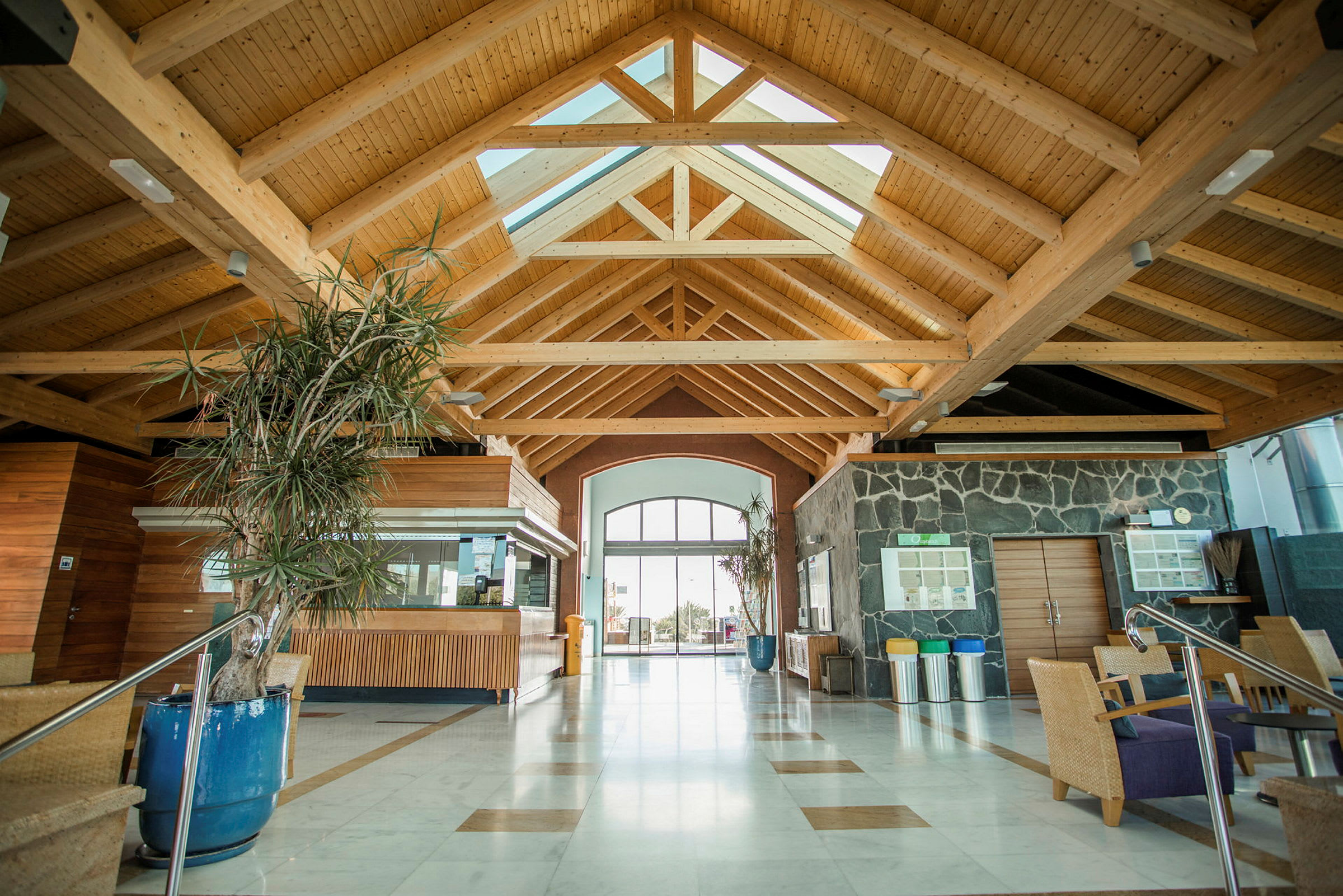 Lobby med højt træbjælkeloft, panoramavinduer og moderne indretning. (AI-genereret tekst)