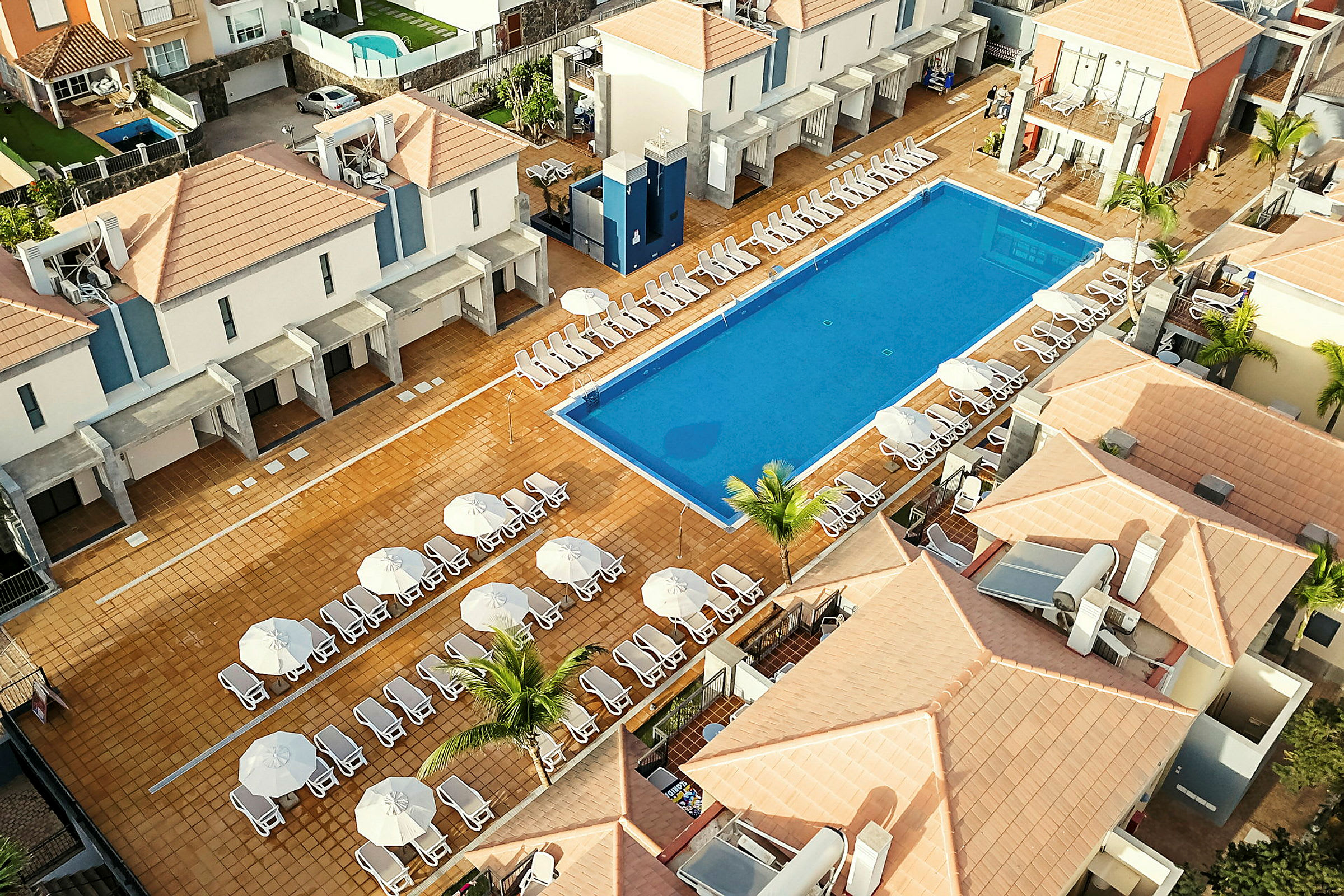 Et hotelområde med pool og solsenge. (AI-genereret tekst)