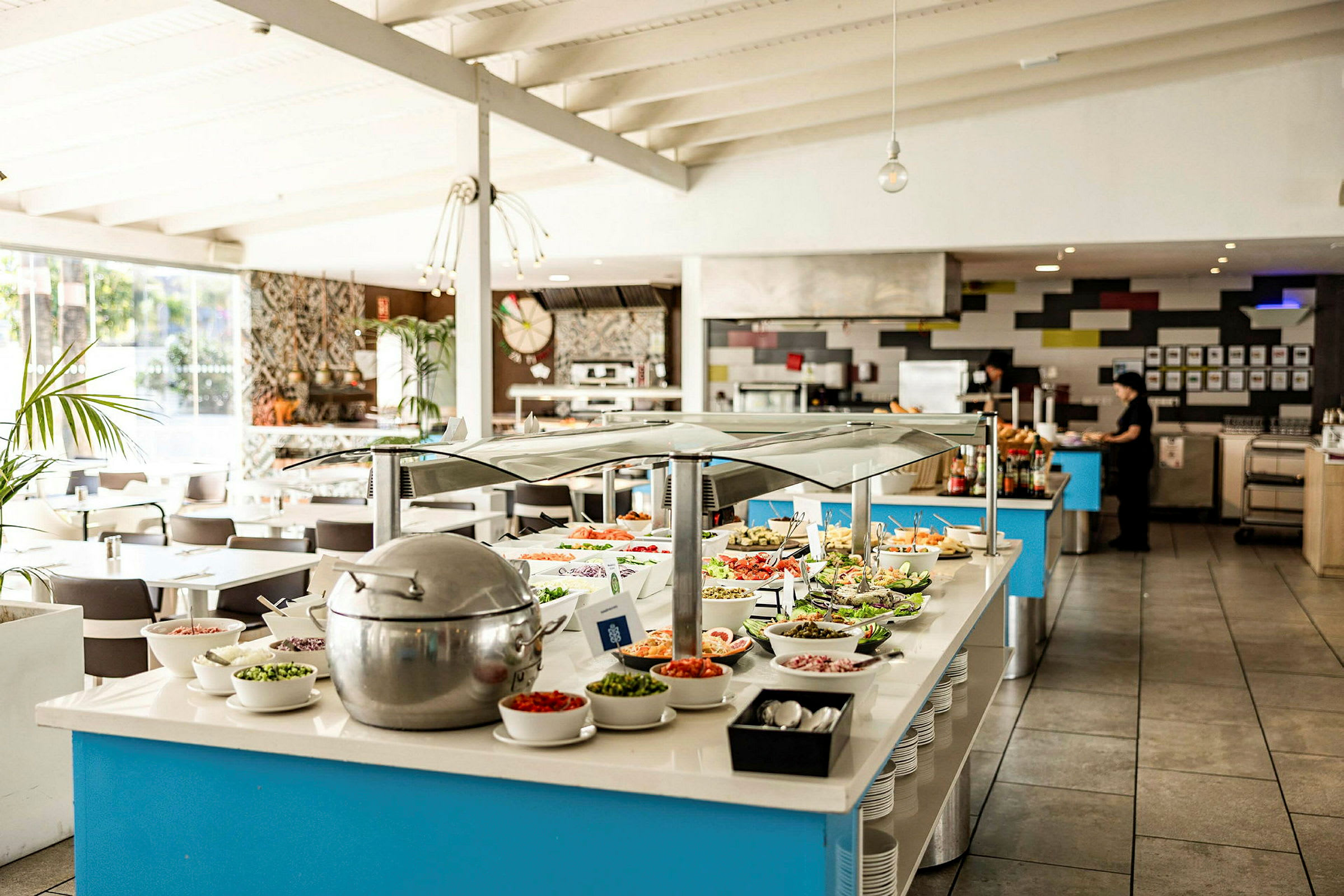 Et buffetbord i en lys restaurant, med forskellige retter og ingredienser anrettet. (AI-genereret tekst)