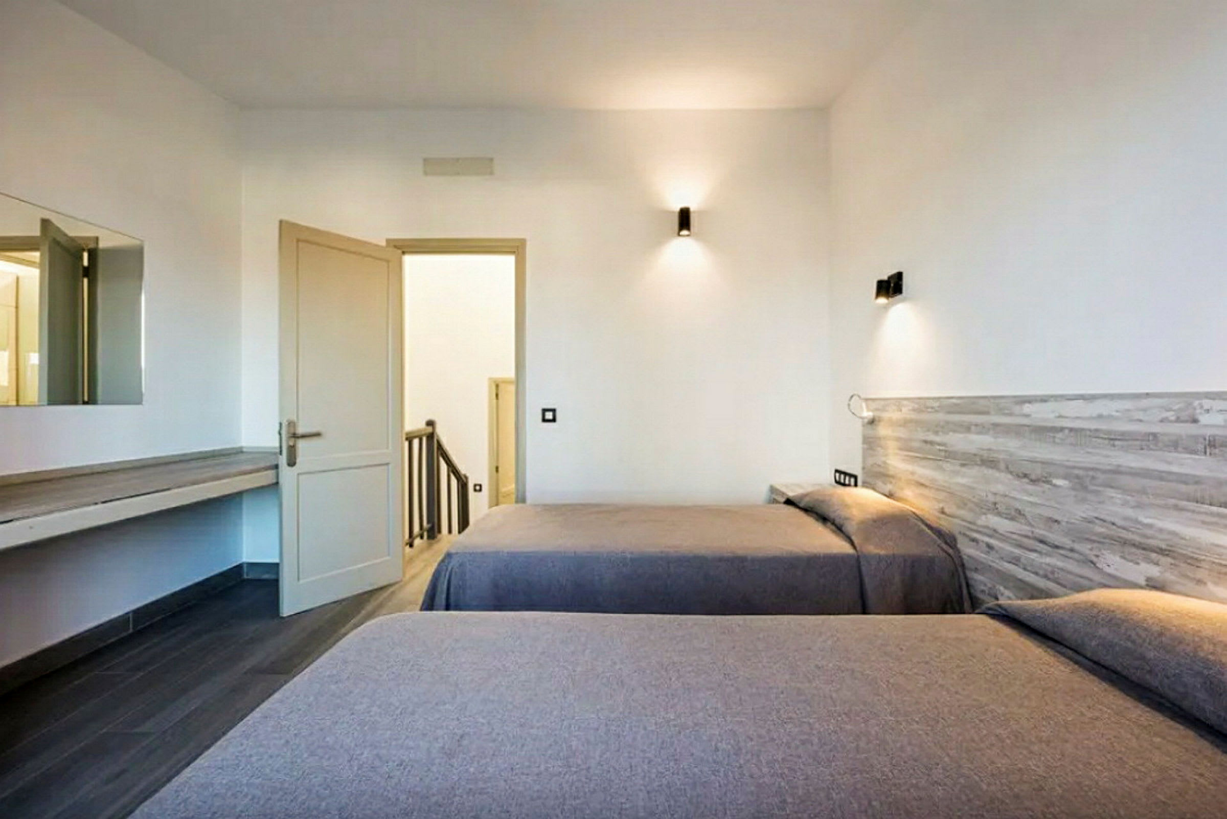 Hotelværelse med to enkeltsenge og en åben dør, der fører til en trappeopgang. (AI-genereret tekst)