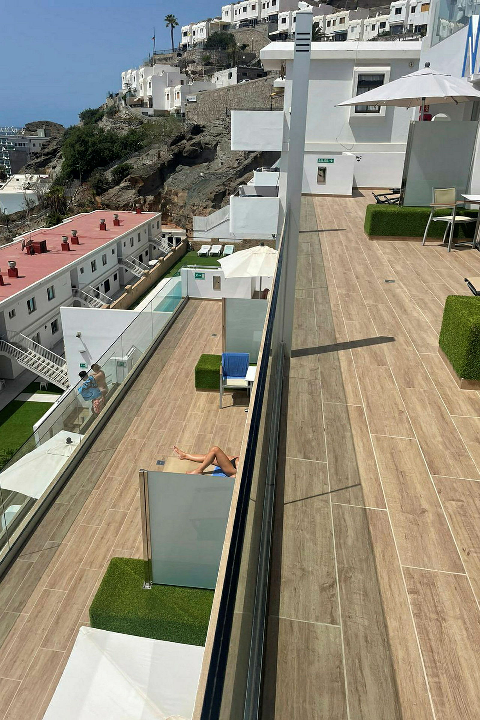 En solterrasse med udsigt over et hotelområde på en bjergskråning. (AI-genereret tekst)